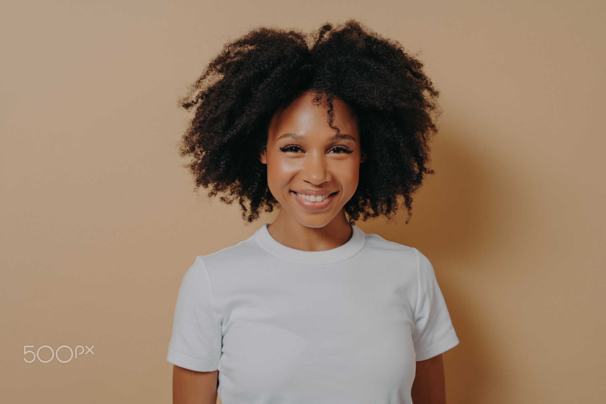 Cheerful woman expressing happiness while standing on beige background