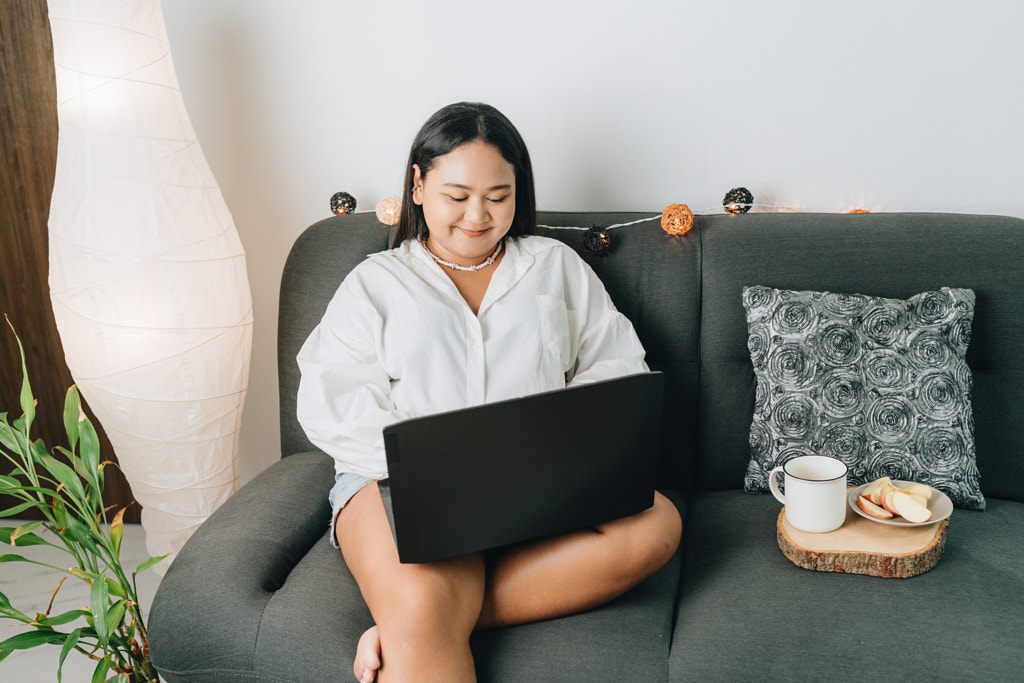 Portrait of a freelancer sitting on the couch and using laptop at home by Natalie Zotova on 500px.com