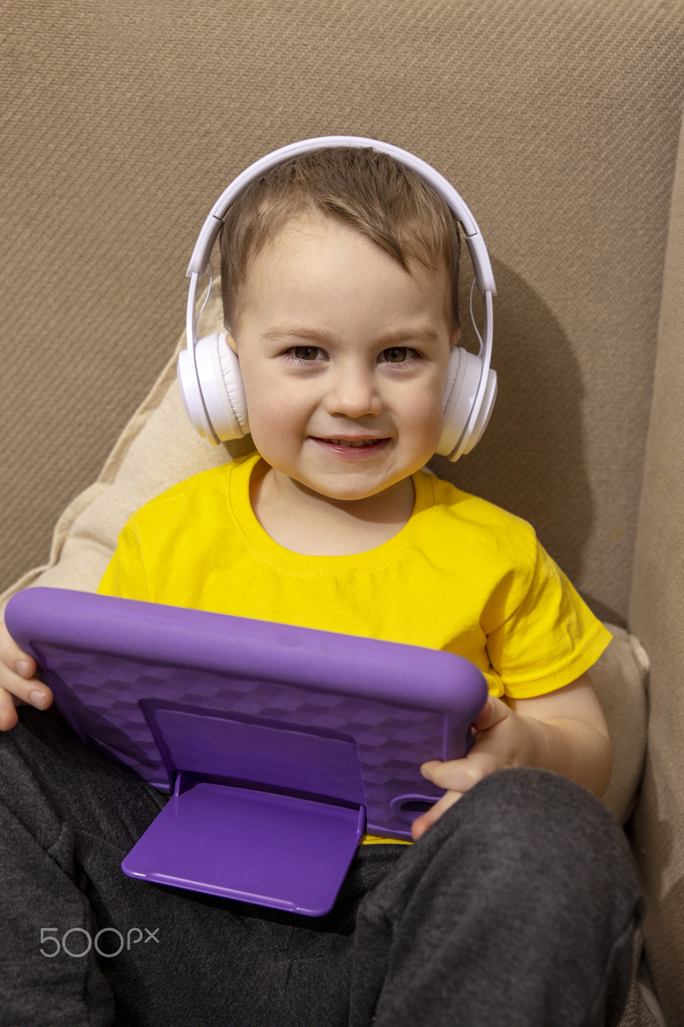 Little caucasian boy with yellow shirt playing game on digital tablet