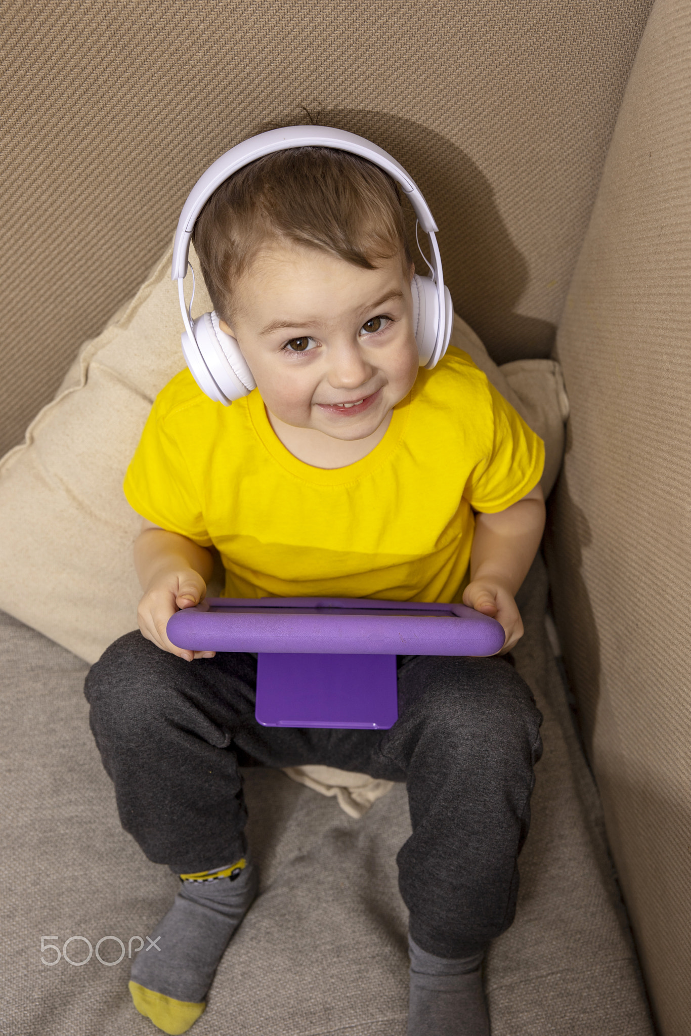 Little caucasian boy with yellow shirt playing game on digital tablet