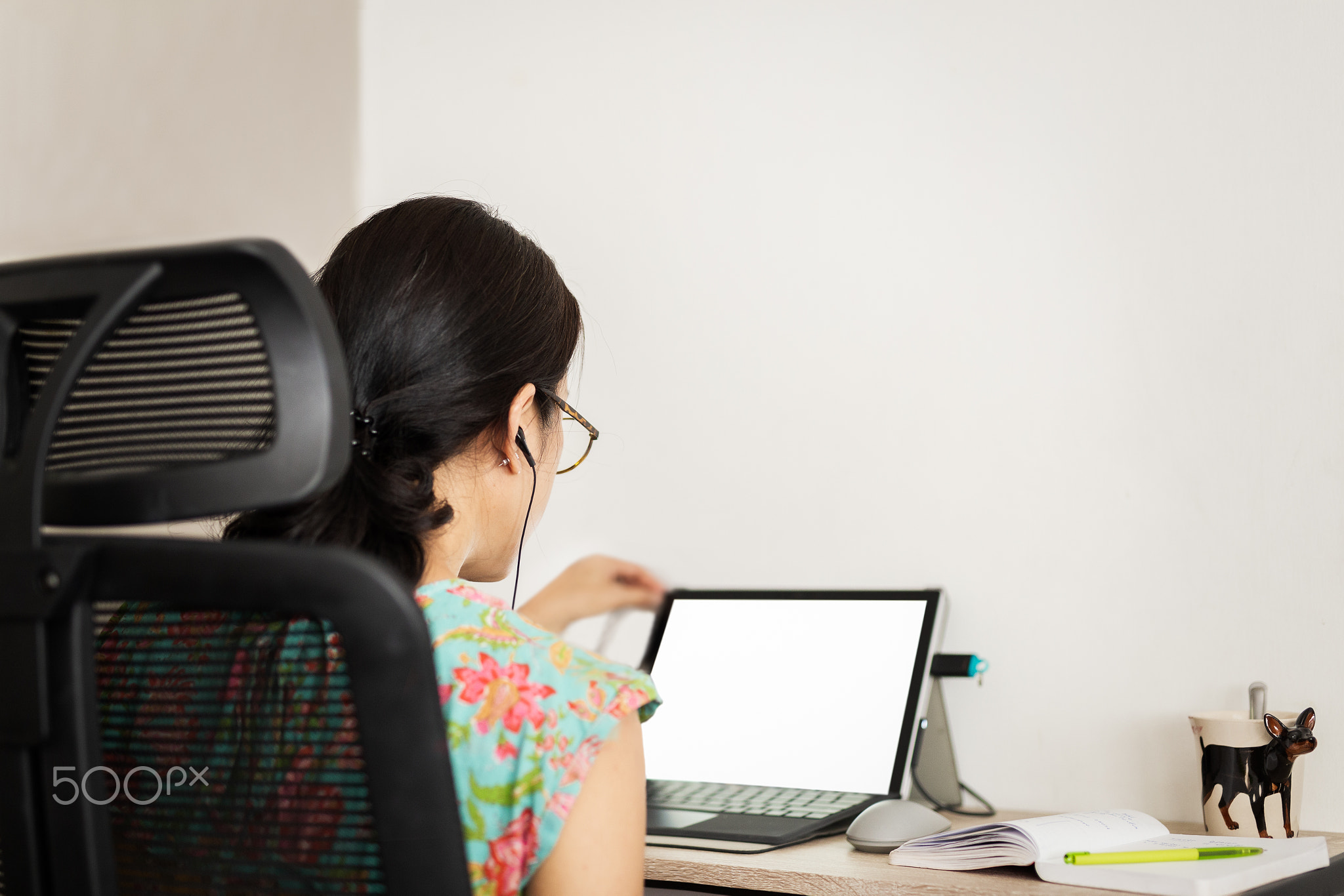 Back view of woman in earphones making video call on laptop.