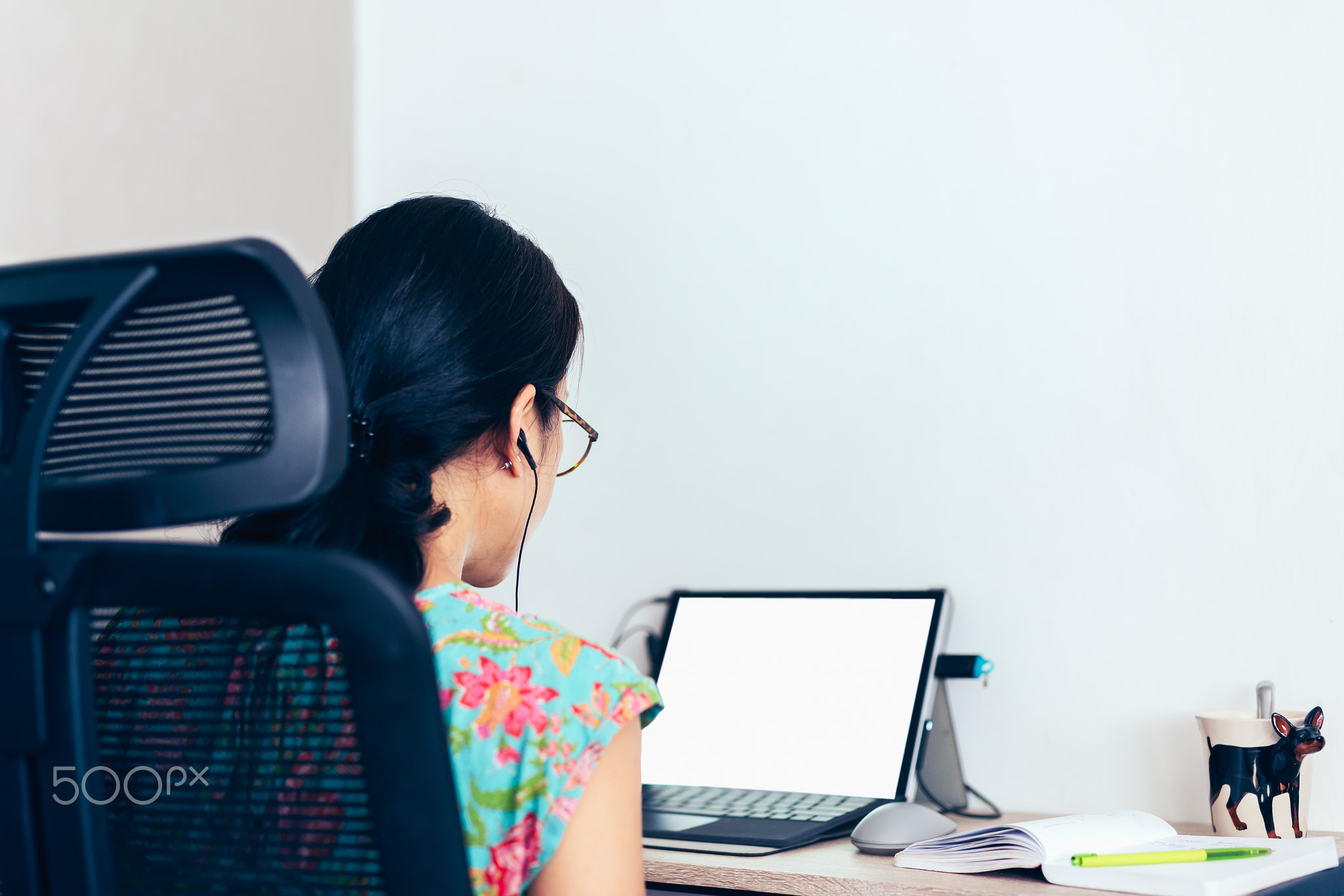 Back view of woman in earphones making video call on laptop.