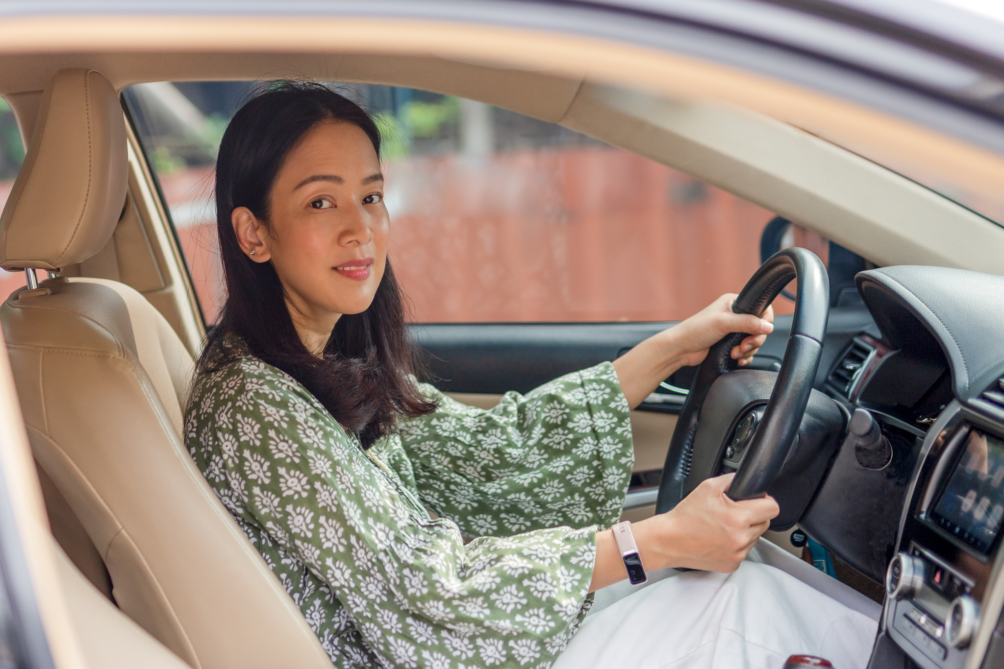 Beautiful Asian woman smiling and enjoying driving a car.