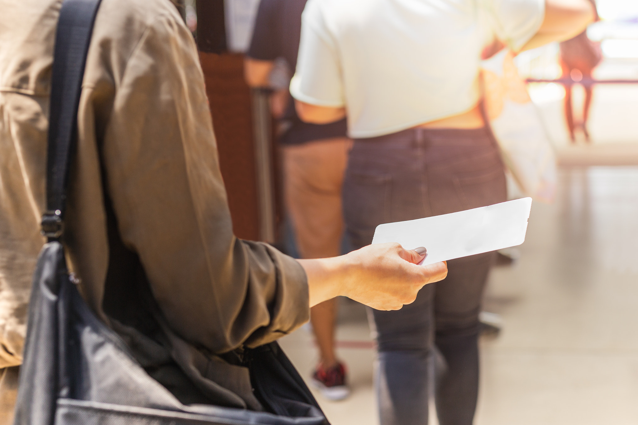 Passengers hand holding boarding pass queueing for departure.