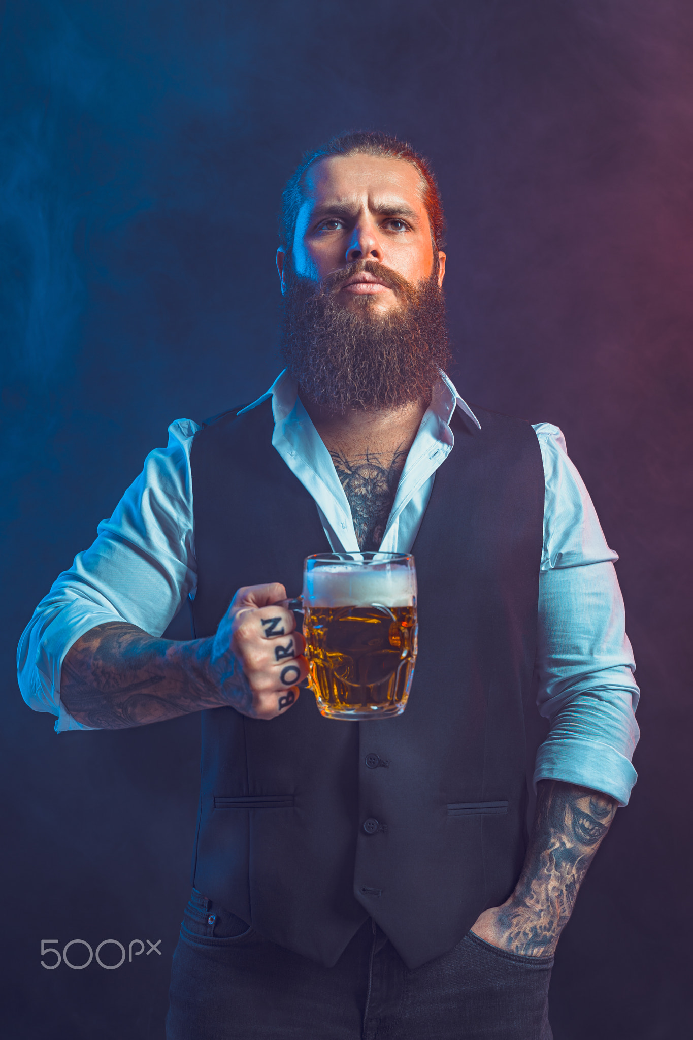 Half length of Bearded man who holds mug of beer looking at camera