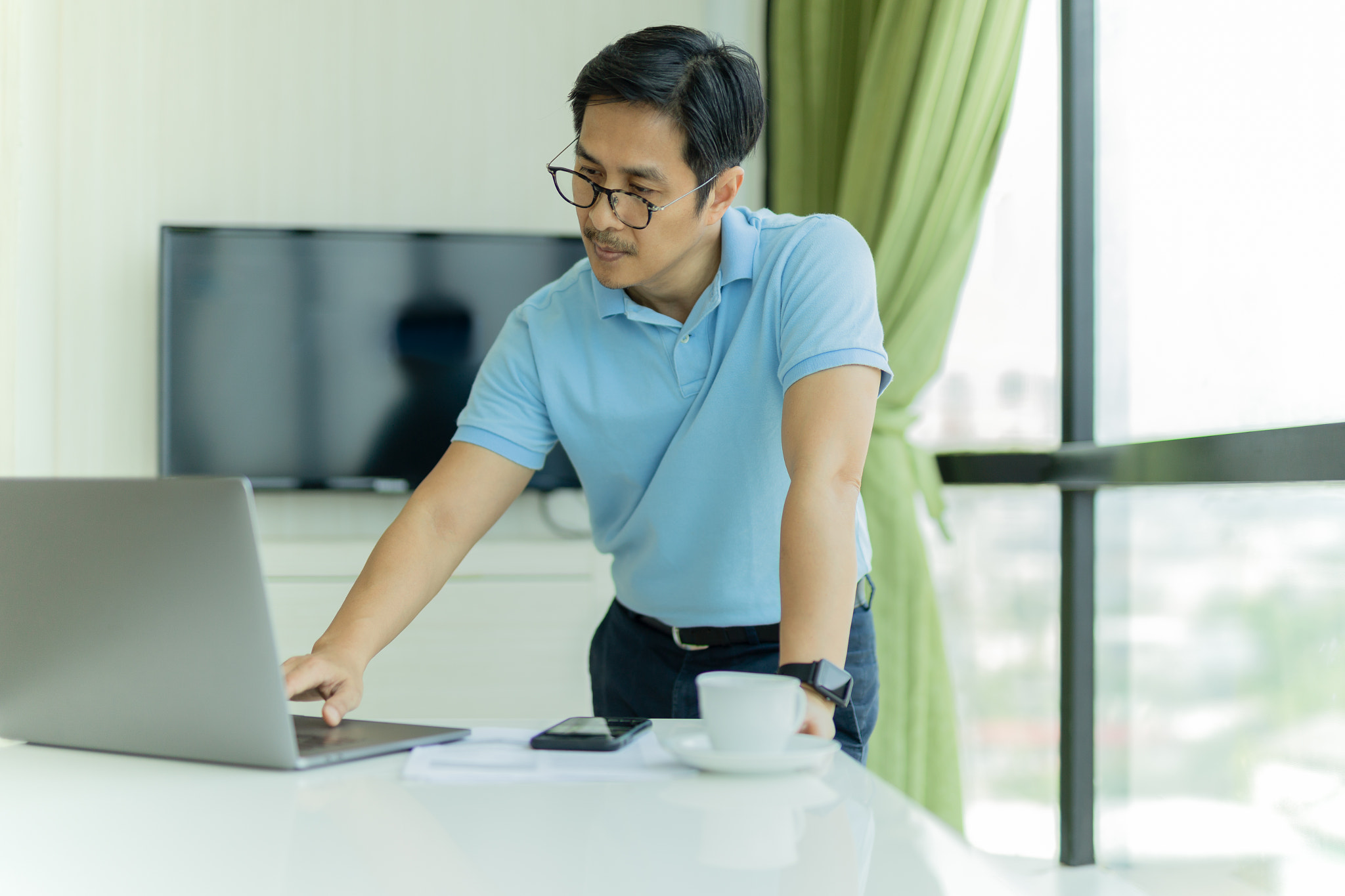 Businessman wearing eyeglasses working on laptop.