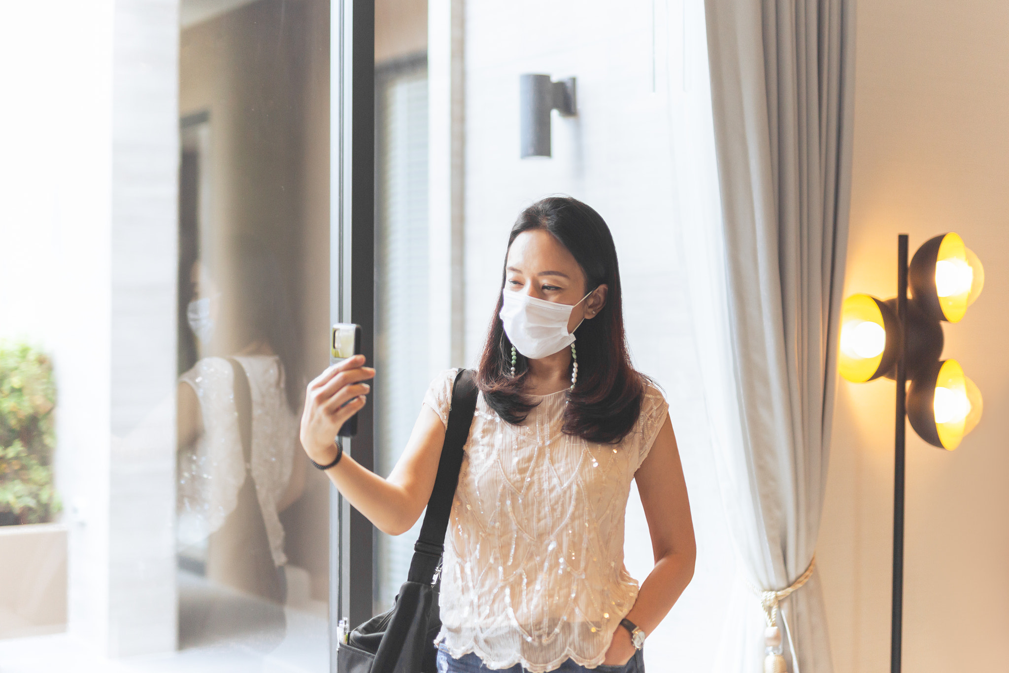 Woman in protective mask make video call from cell phone at home.