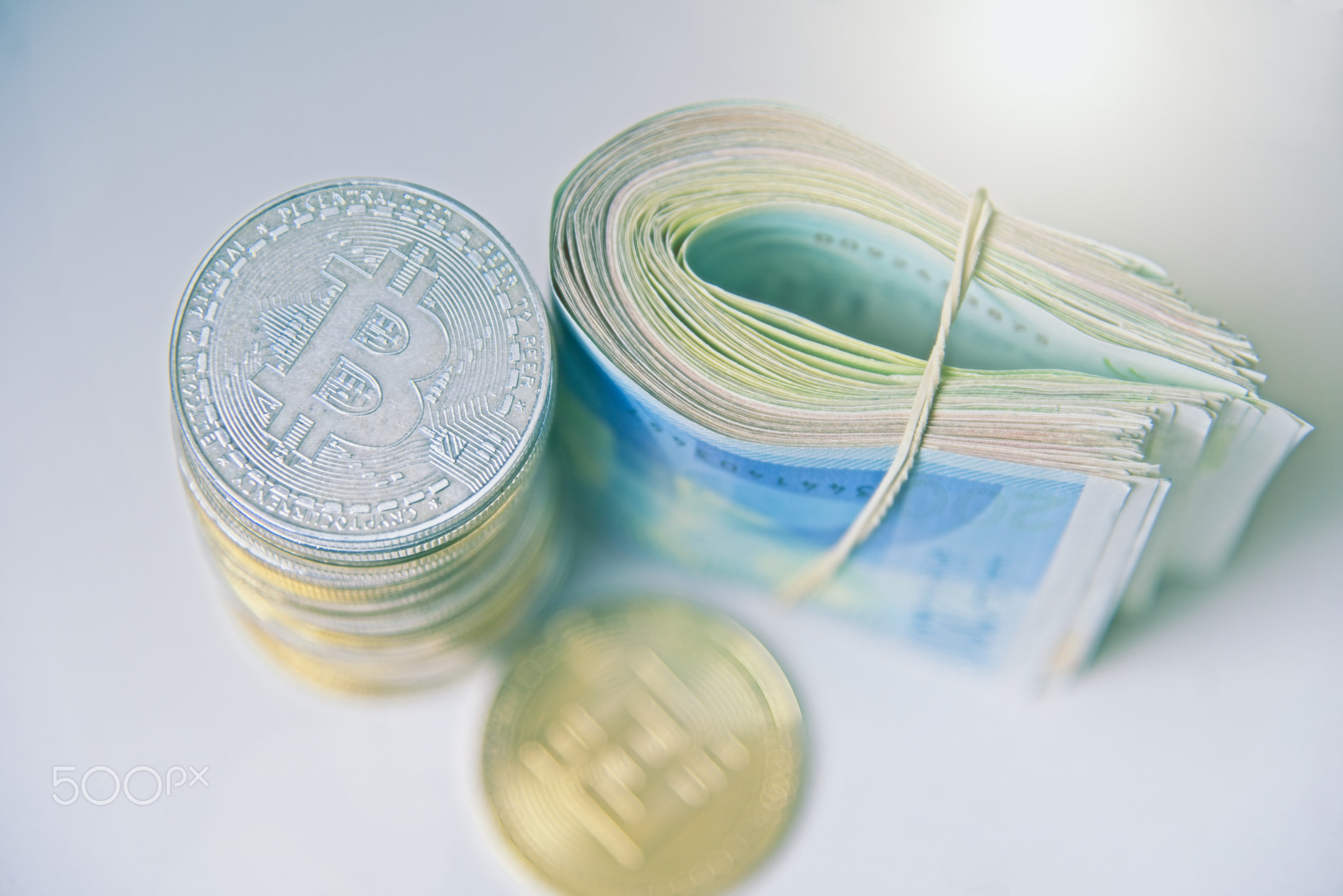 Roll Israeli Shekel ILS banknotes near cryptocurrency tokens Bitcoins