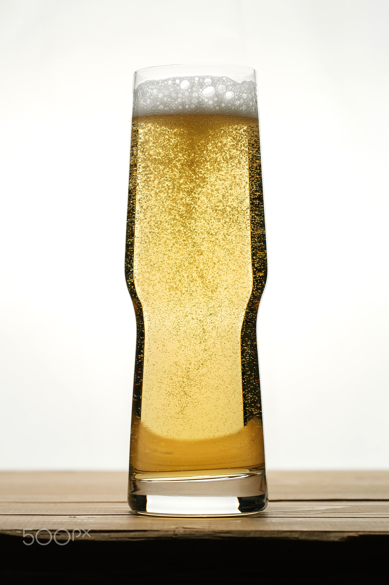 Golden beer with bubbles in a transparent glass.