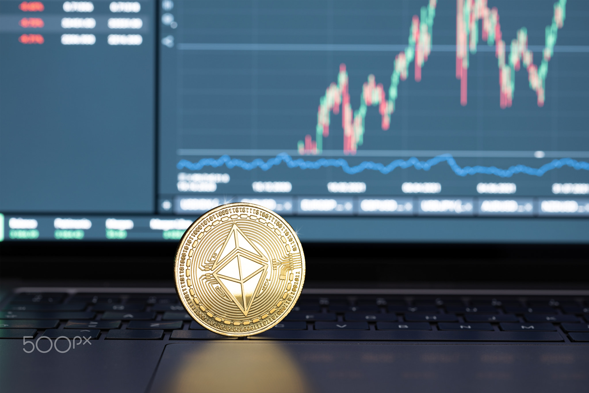 Ethereum coin on laptop and chart on display at background