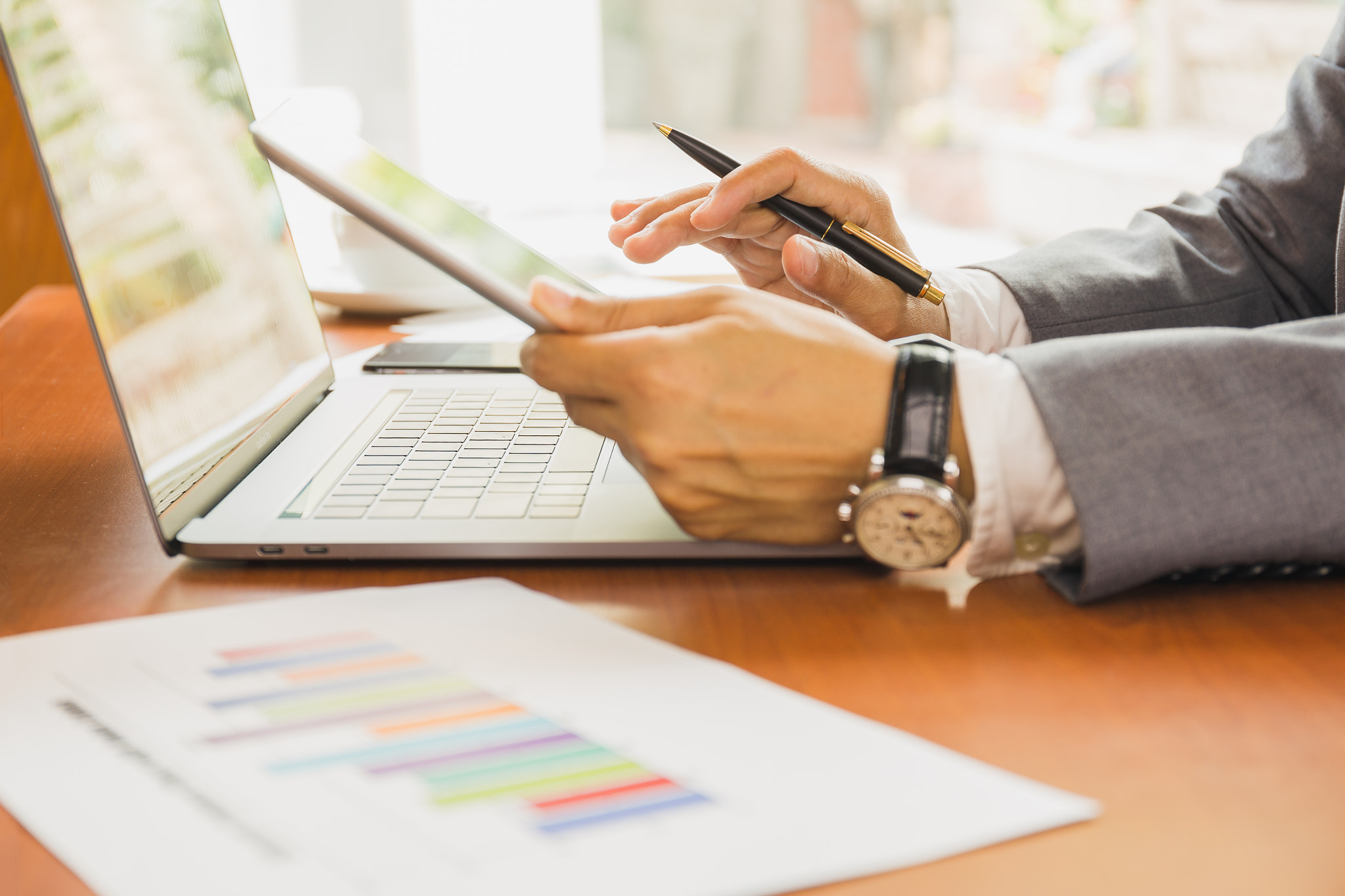 Businessman working on tablet with hand holding financial graph.