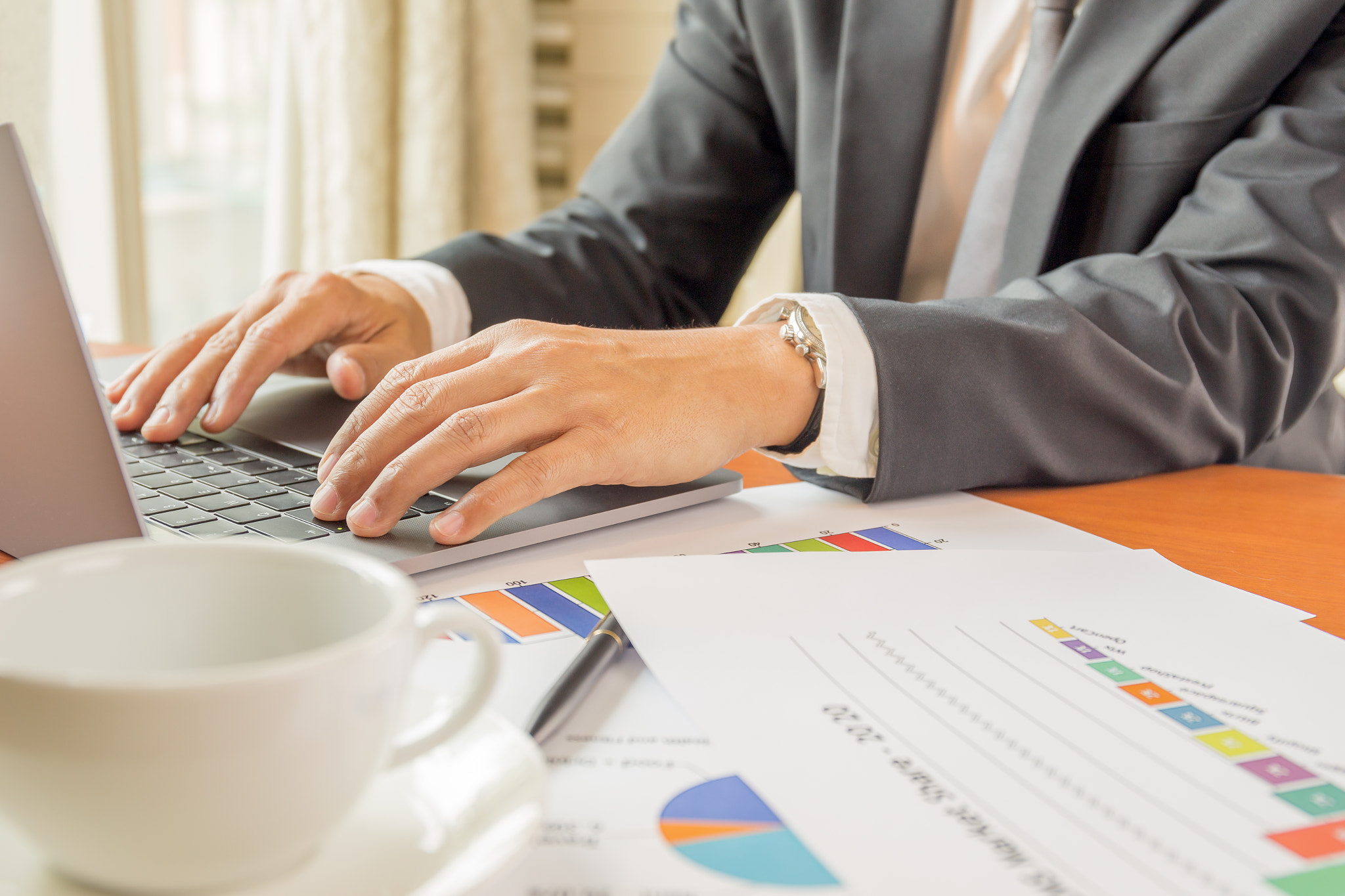 Businessman working on laptop with financial graph report.