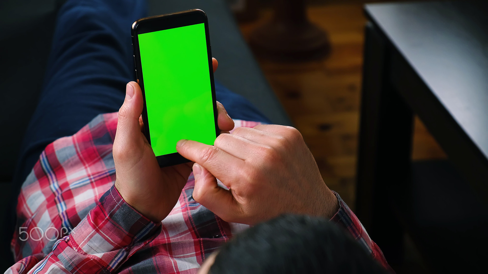 A man holds a phone in his hands with a green screen. Selective focus.