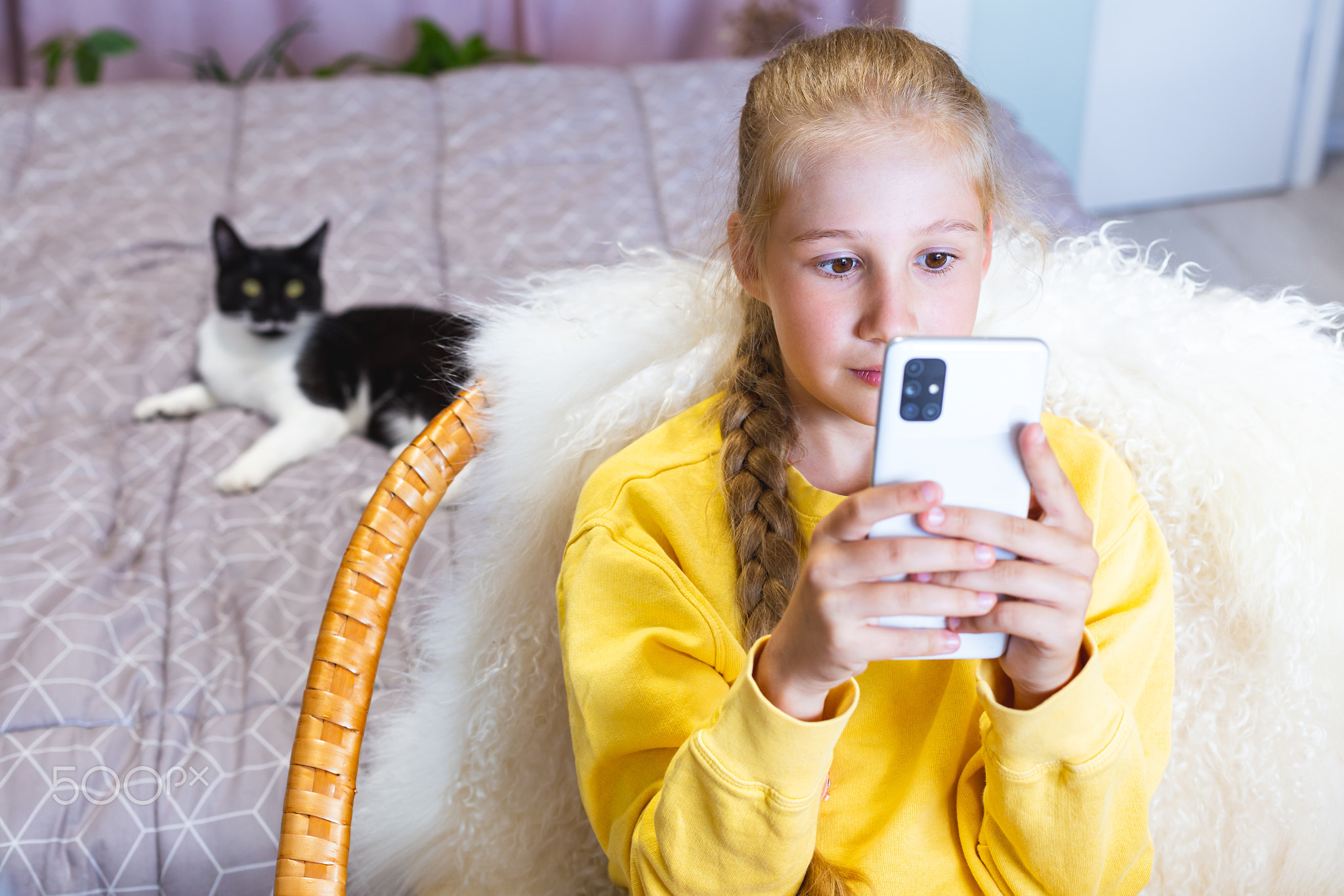 Girl in yellow sweatshirt looking at screen of mobile phone, holding