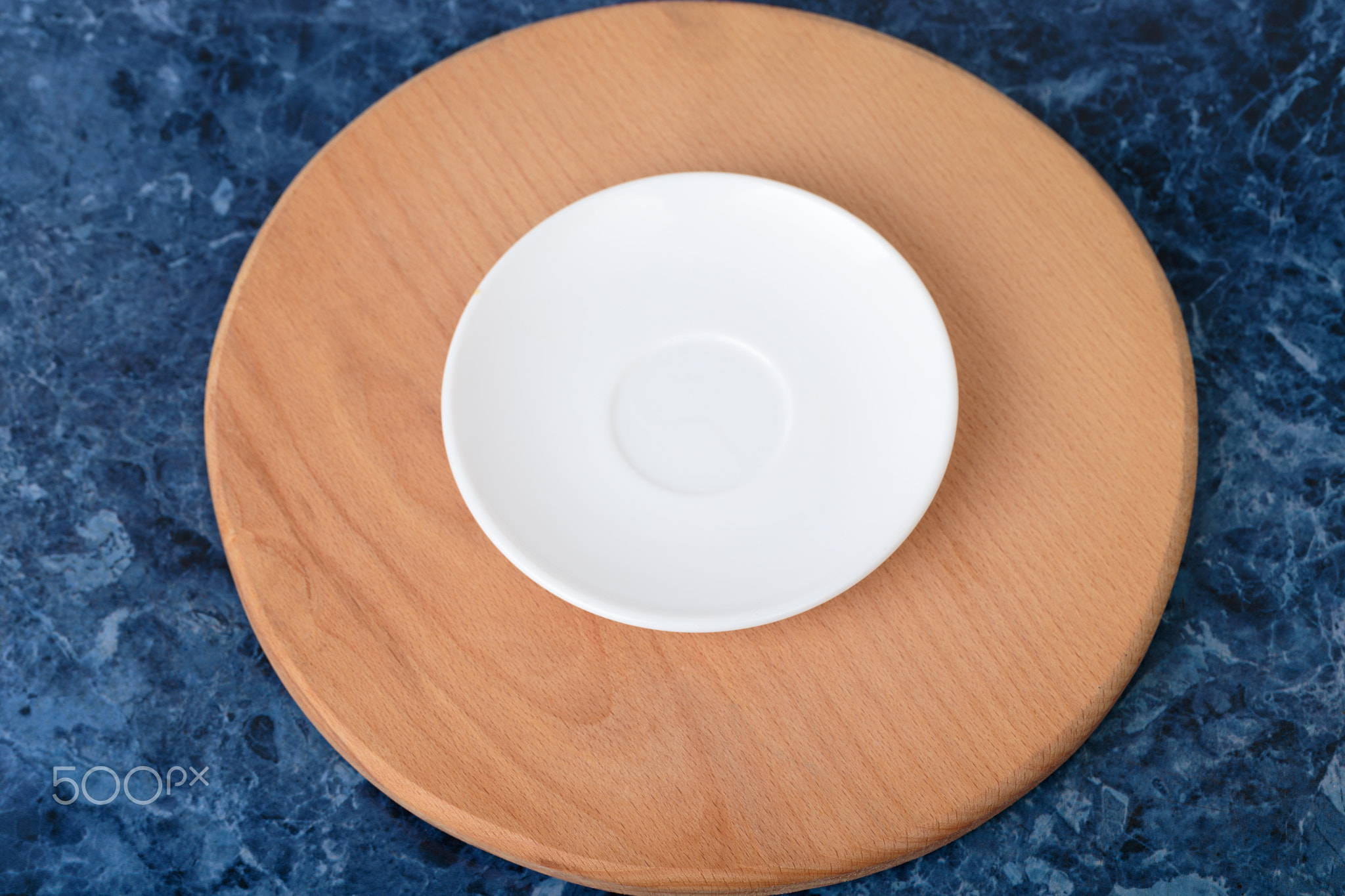 The porcelain saucer is on a wooden cutting board.