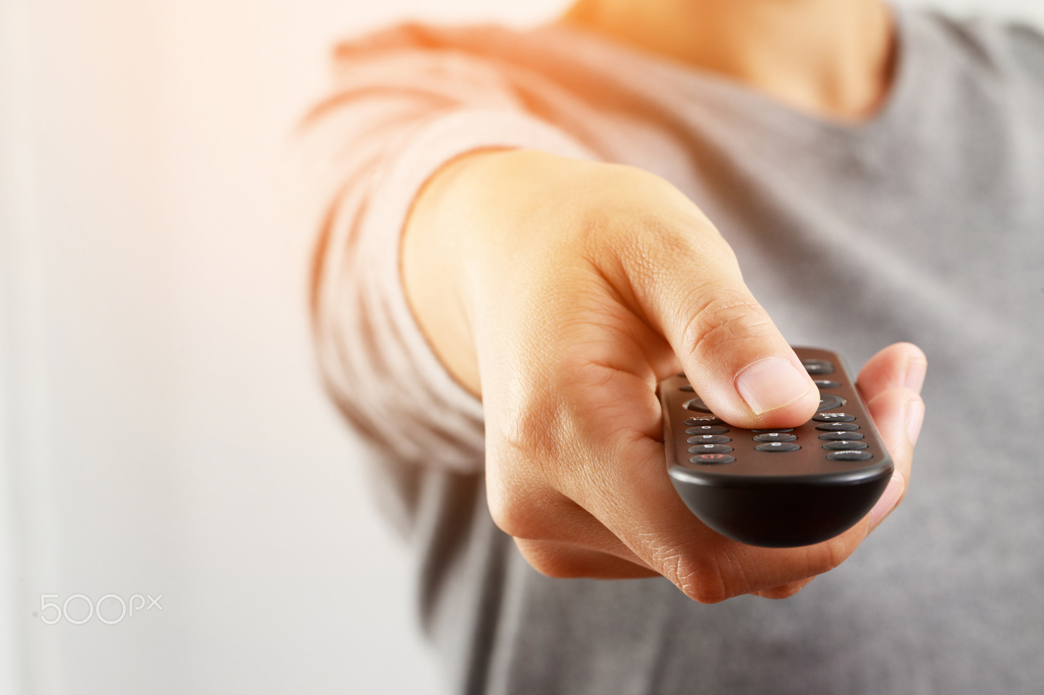 Woman presses online TV remote at home