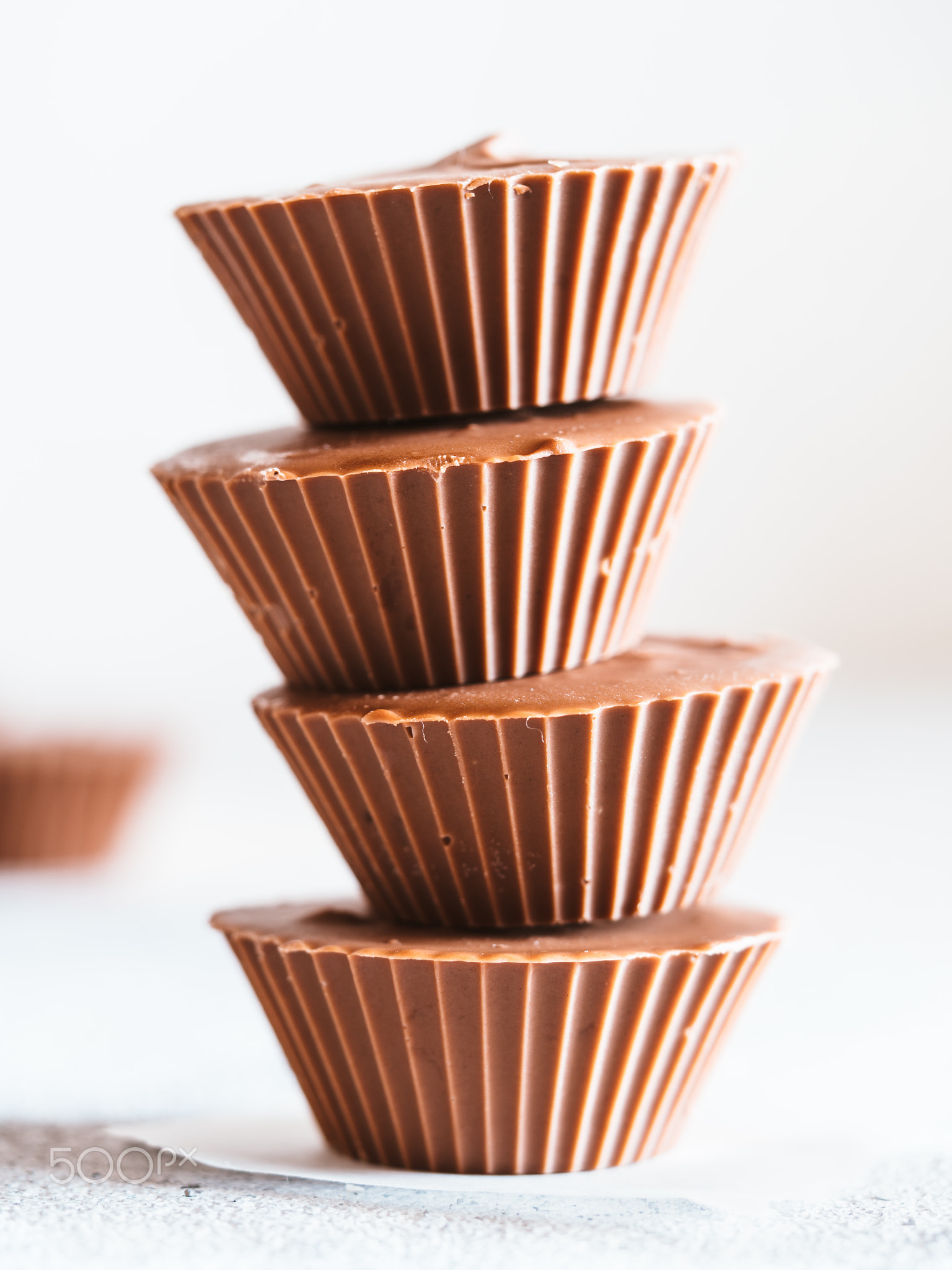 Stack of vegan chocolate cups with caramel on white