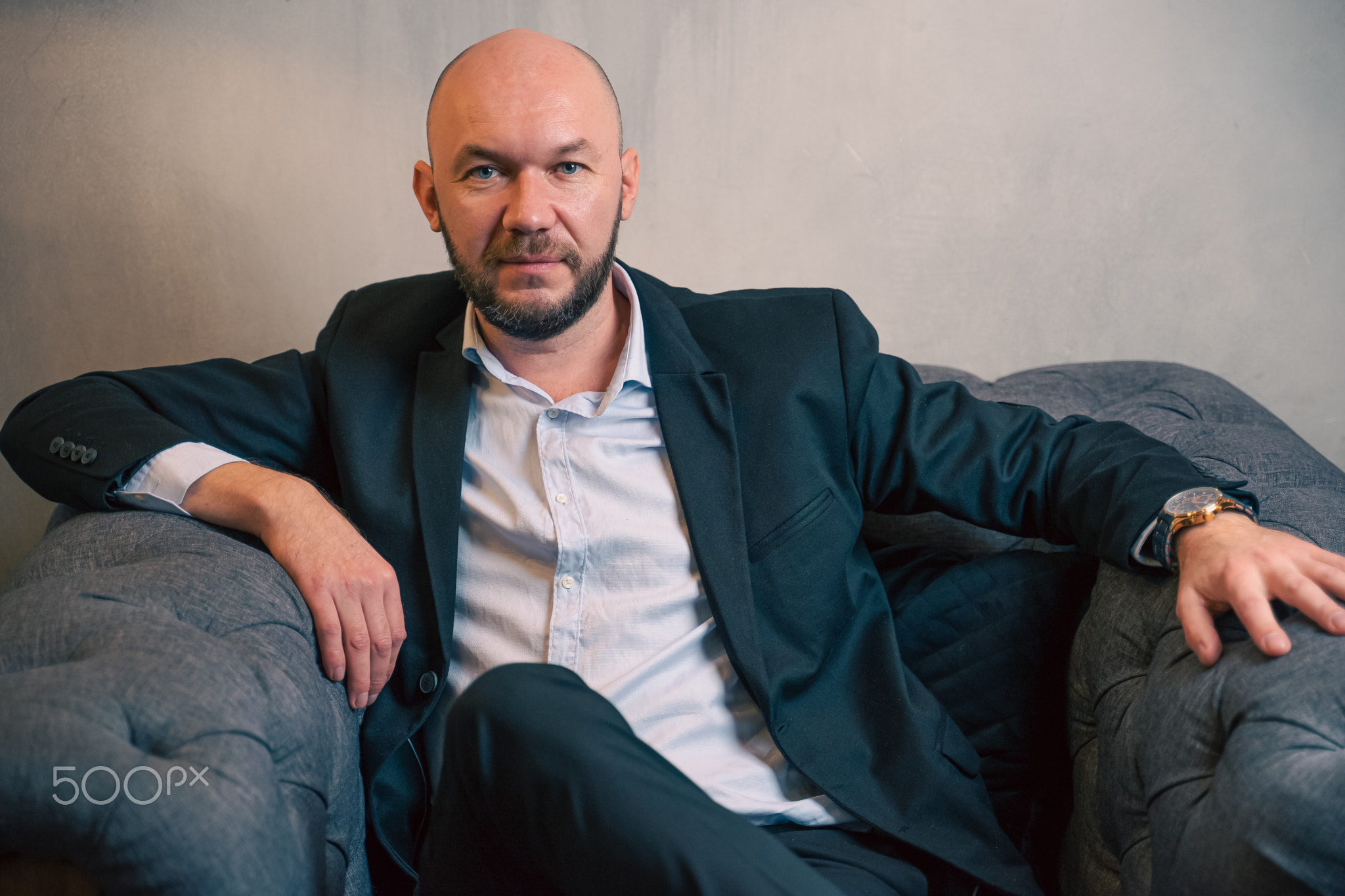A man sits in an expensive chair. Business portrait of a bald man