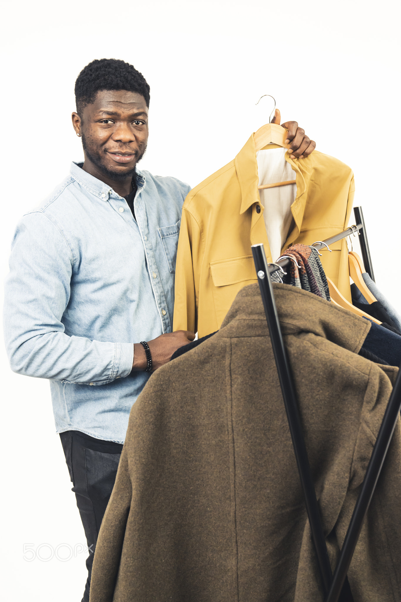 black man smiling showing yellow jacket clothe rack white background -