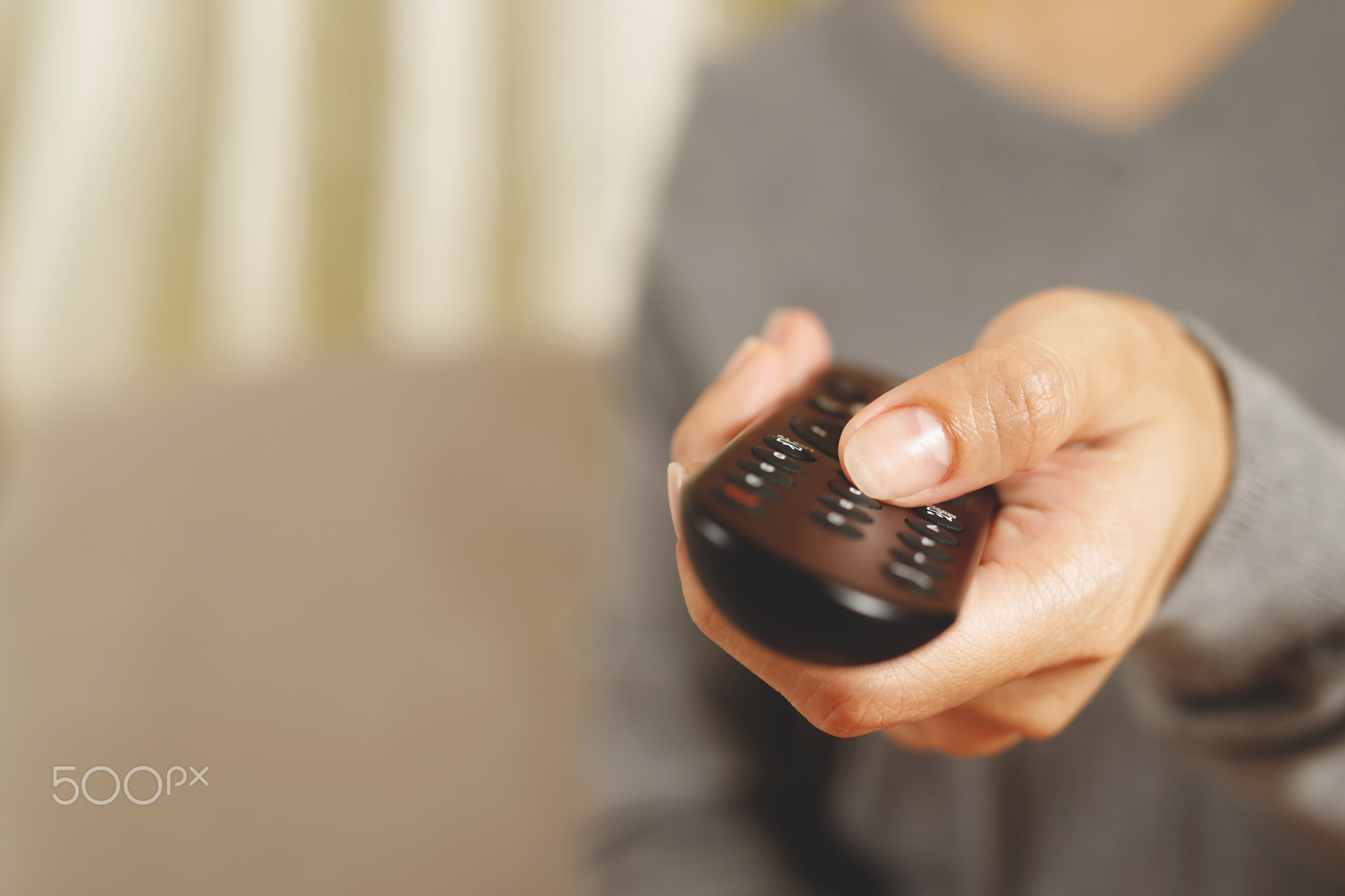 Woman presses online TV remote at home