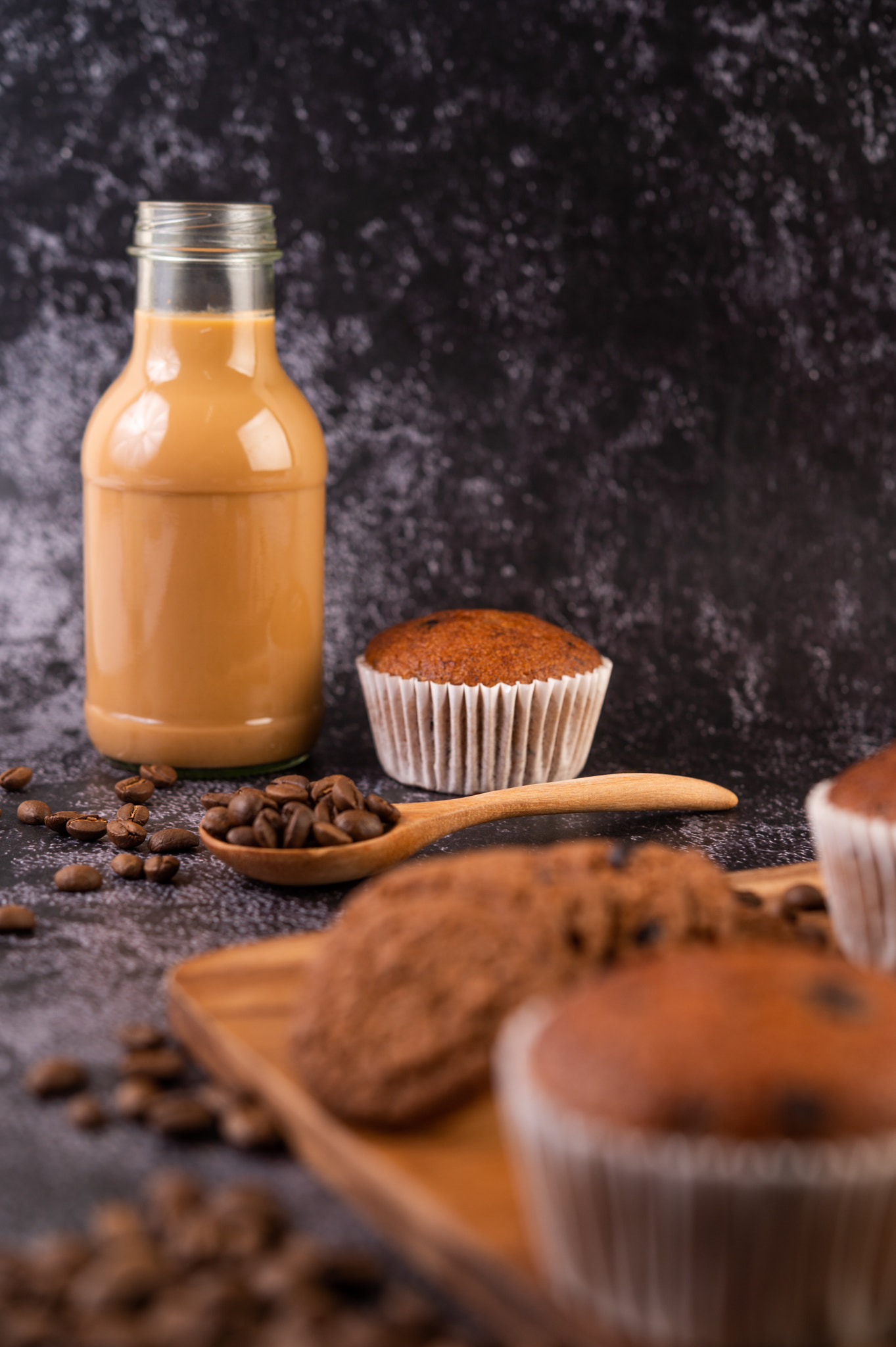 Banana cupcakes that are placed on a wooden plate with coffee grains.