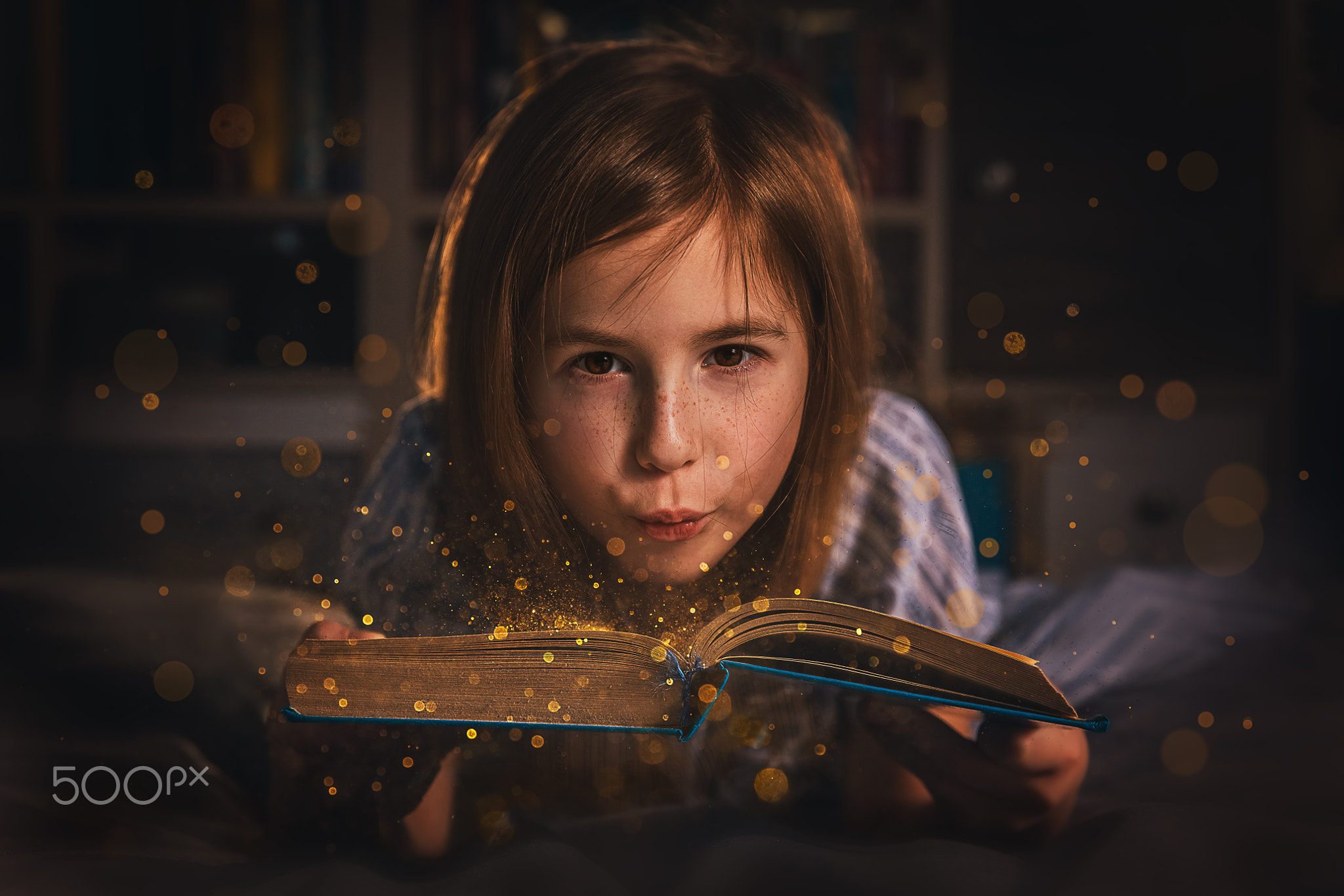 magic photo. a girl blows gold dust off a book