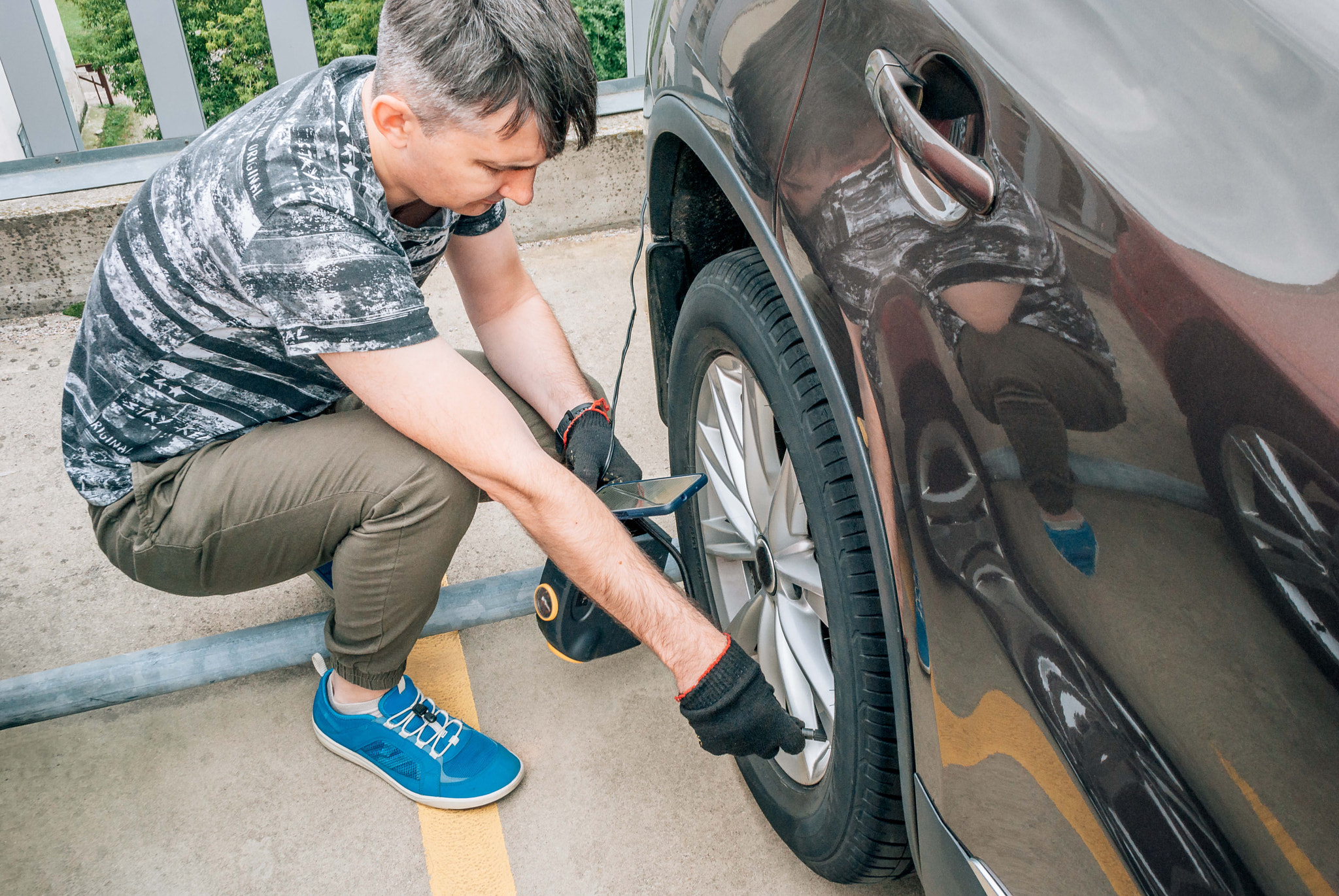 A man pumps the wheel of a car with a pump