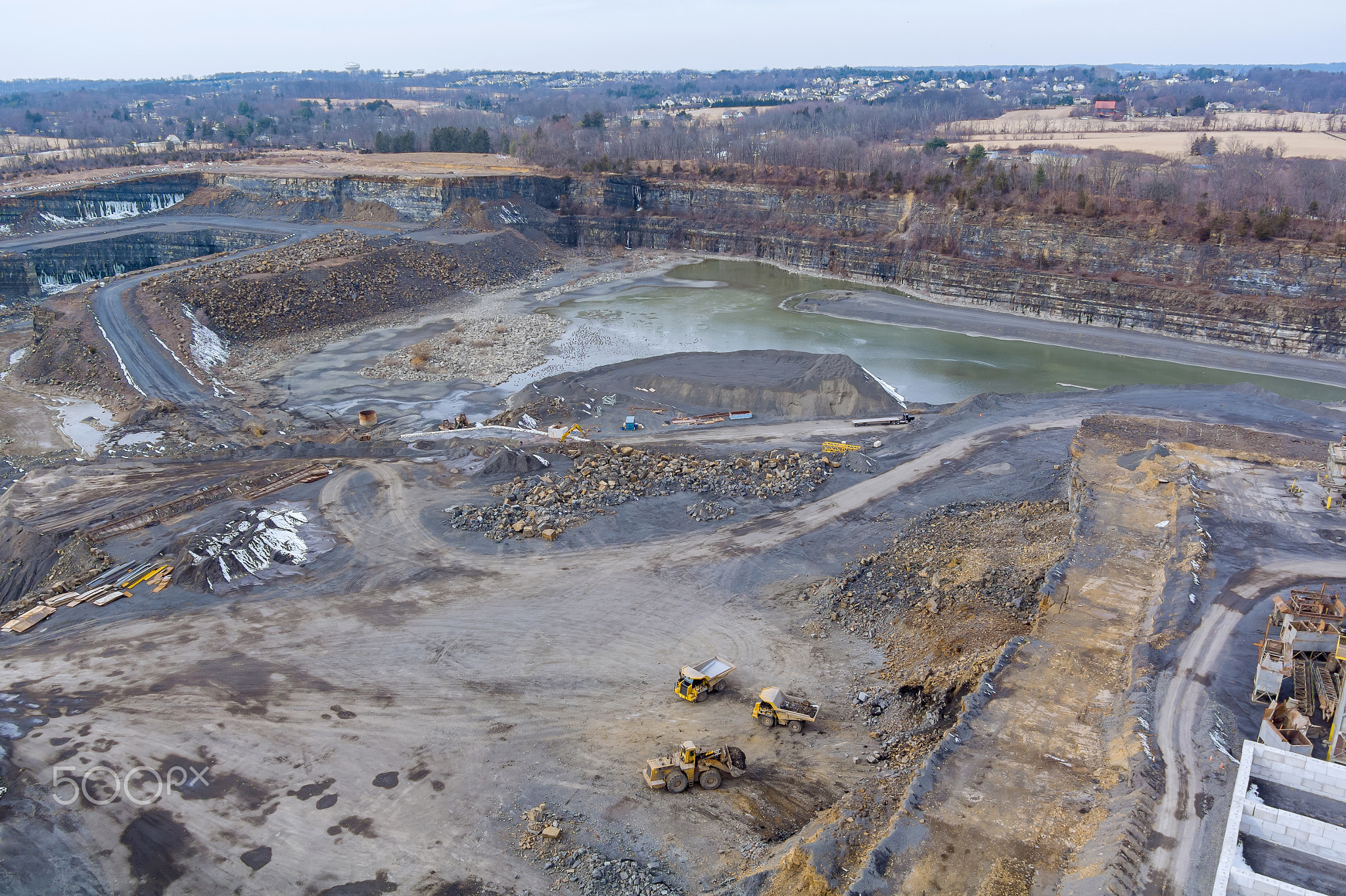 Heavy mining dump trucks driving along the opencast of excavator loads