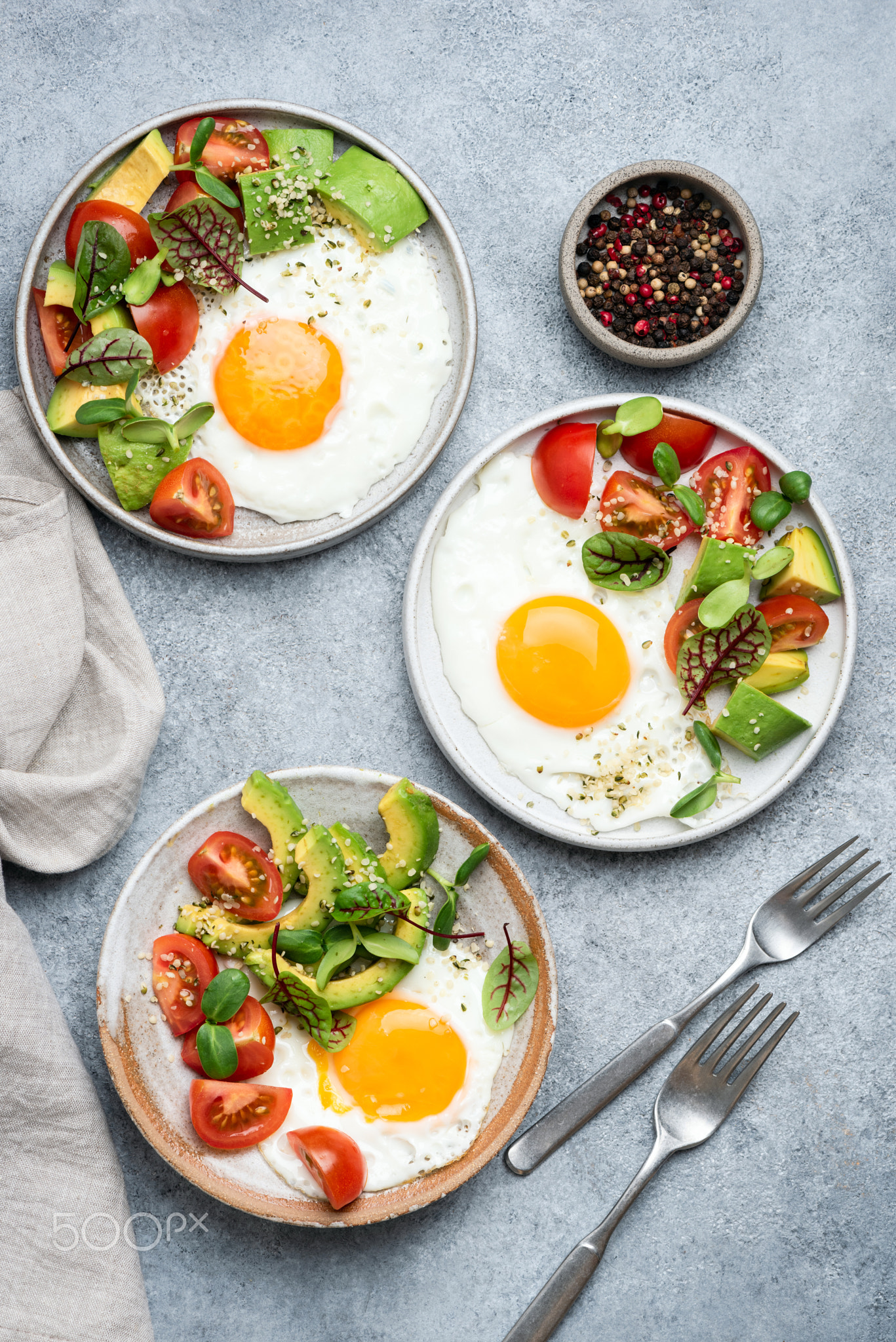 Fried egg with tomato avocado salad, seeds and sprouts