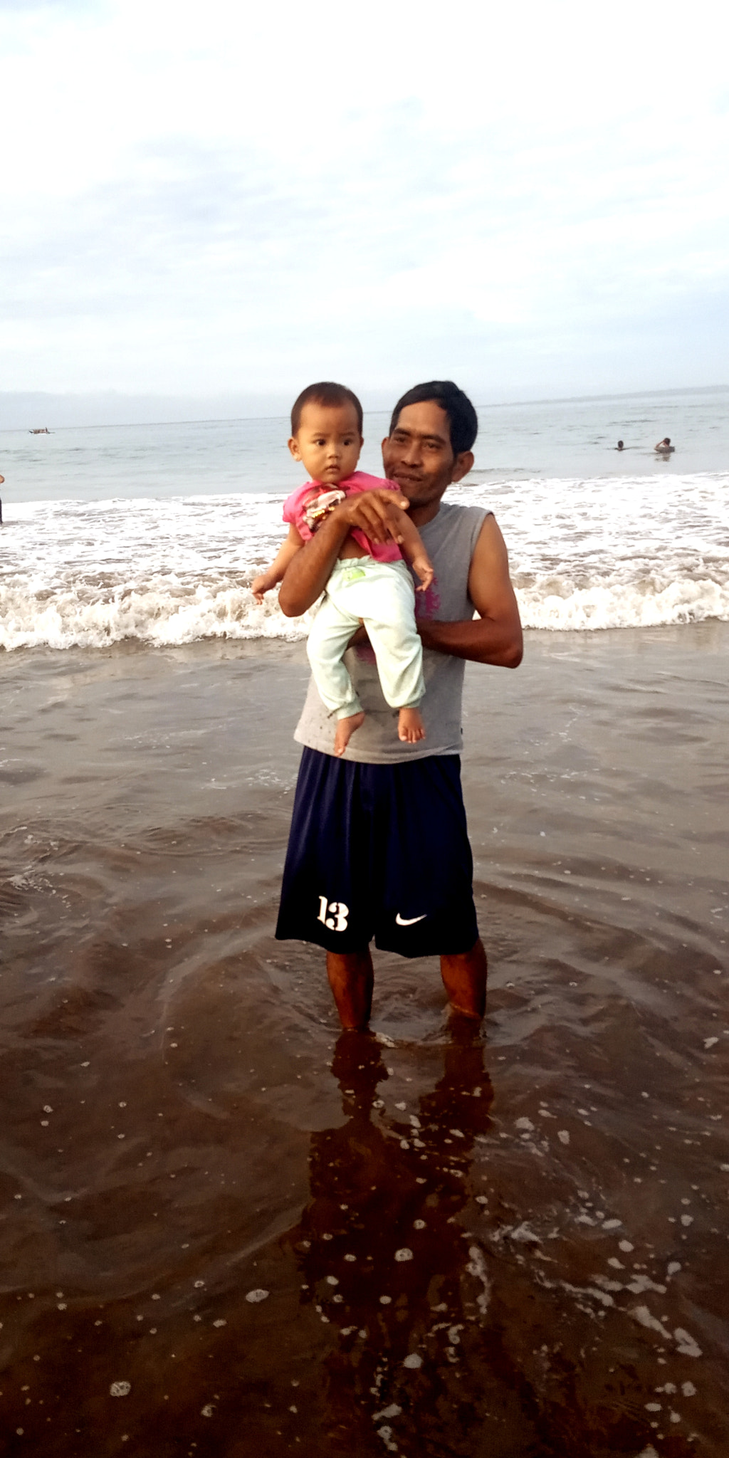 portrait of smiling mother carrying daughter while standing at beach a