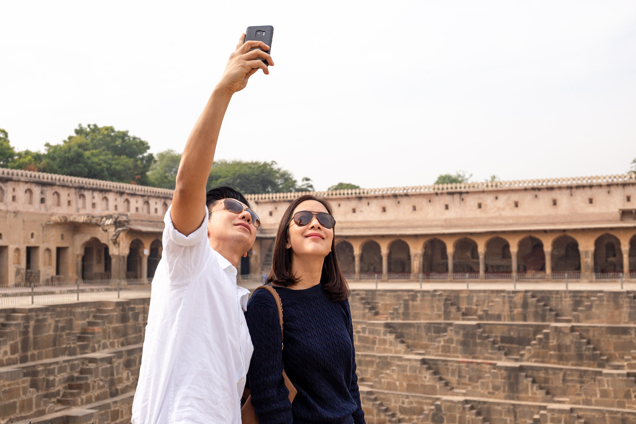 Couple taking selfie with cell phone on Chand Baori Stepwell in india.