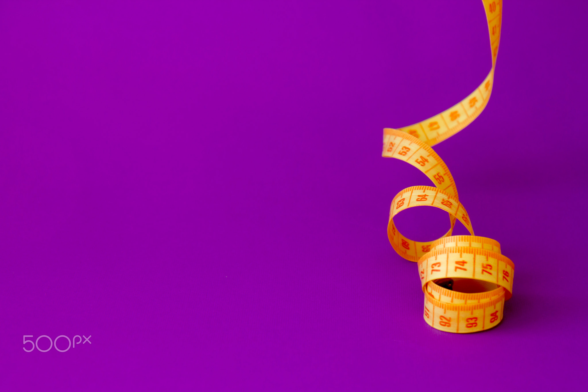 Bright yellow measuring tape a violet background