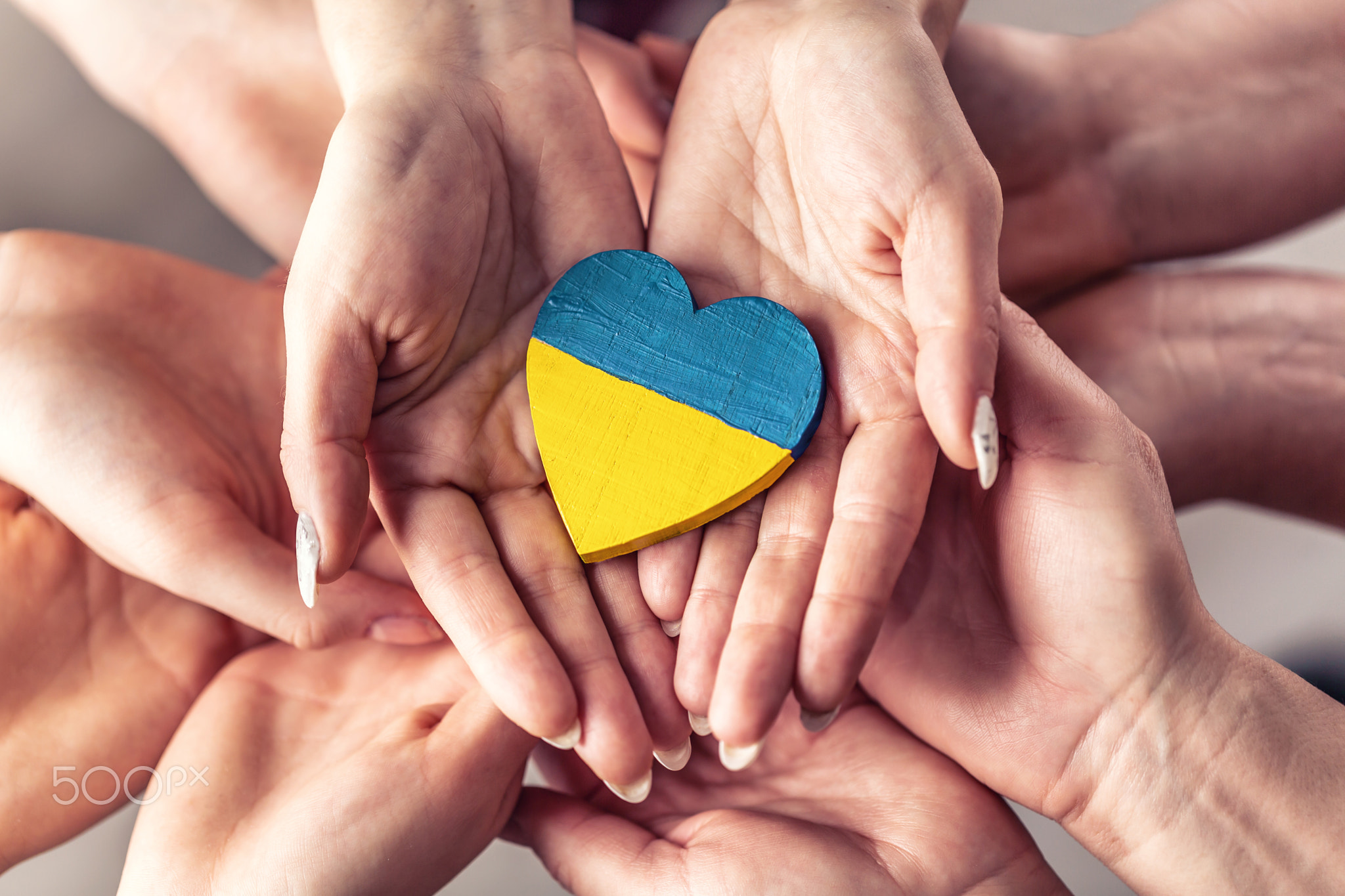 We stand with Ukraine symbol as numerous hands hold wooden heart