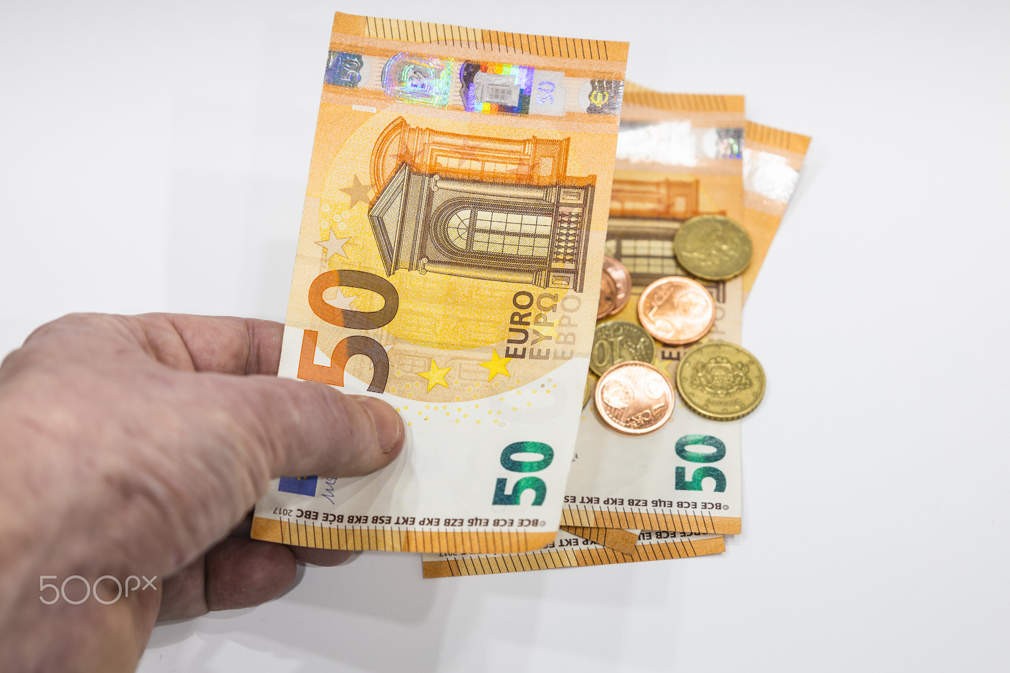 Male hand holding 50 Euro note and coins in the background