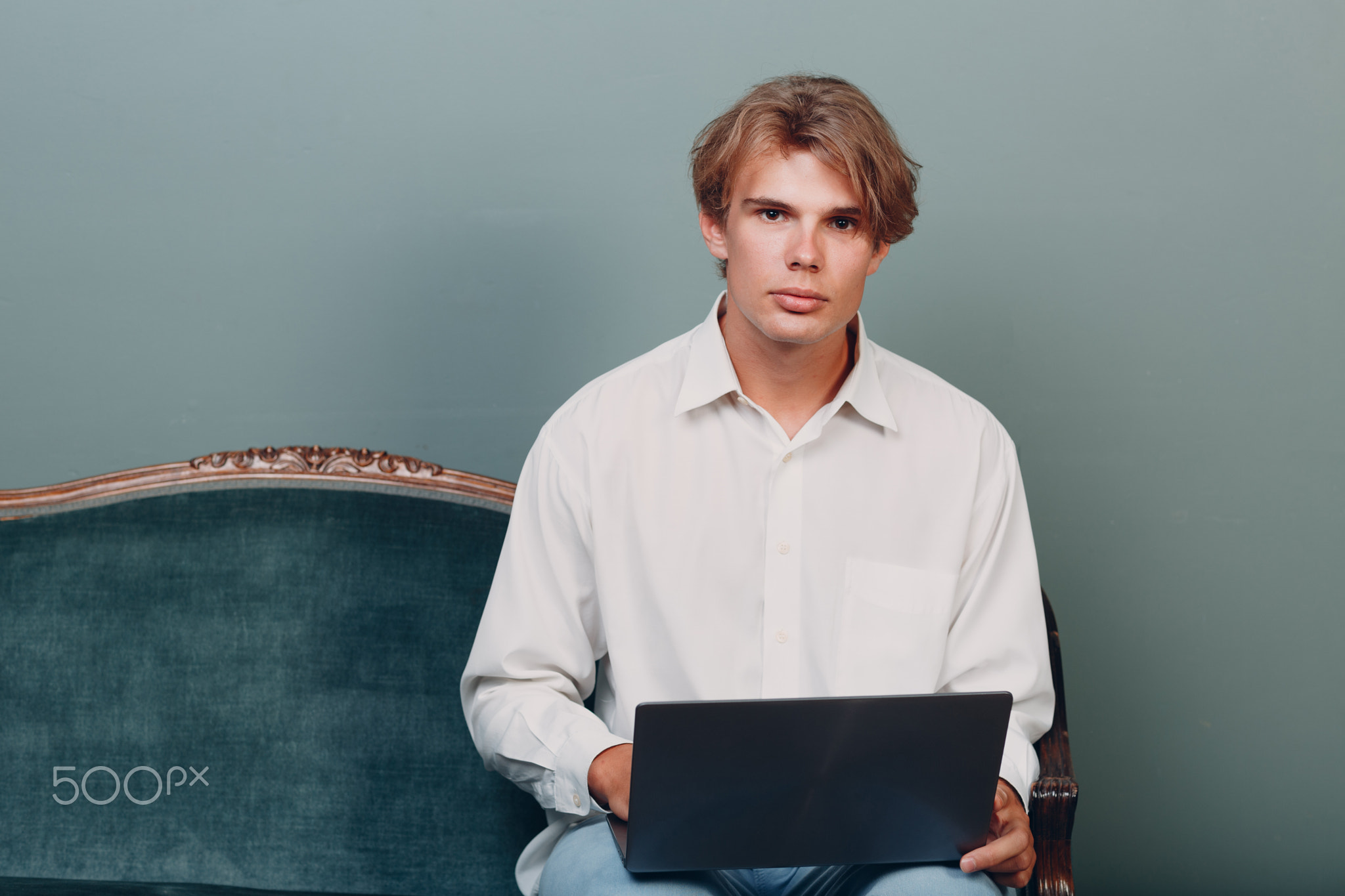 Portrait young man sitting with laptop at studio.
