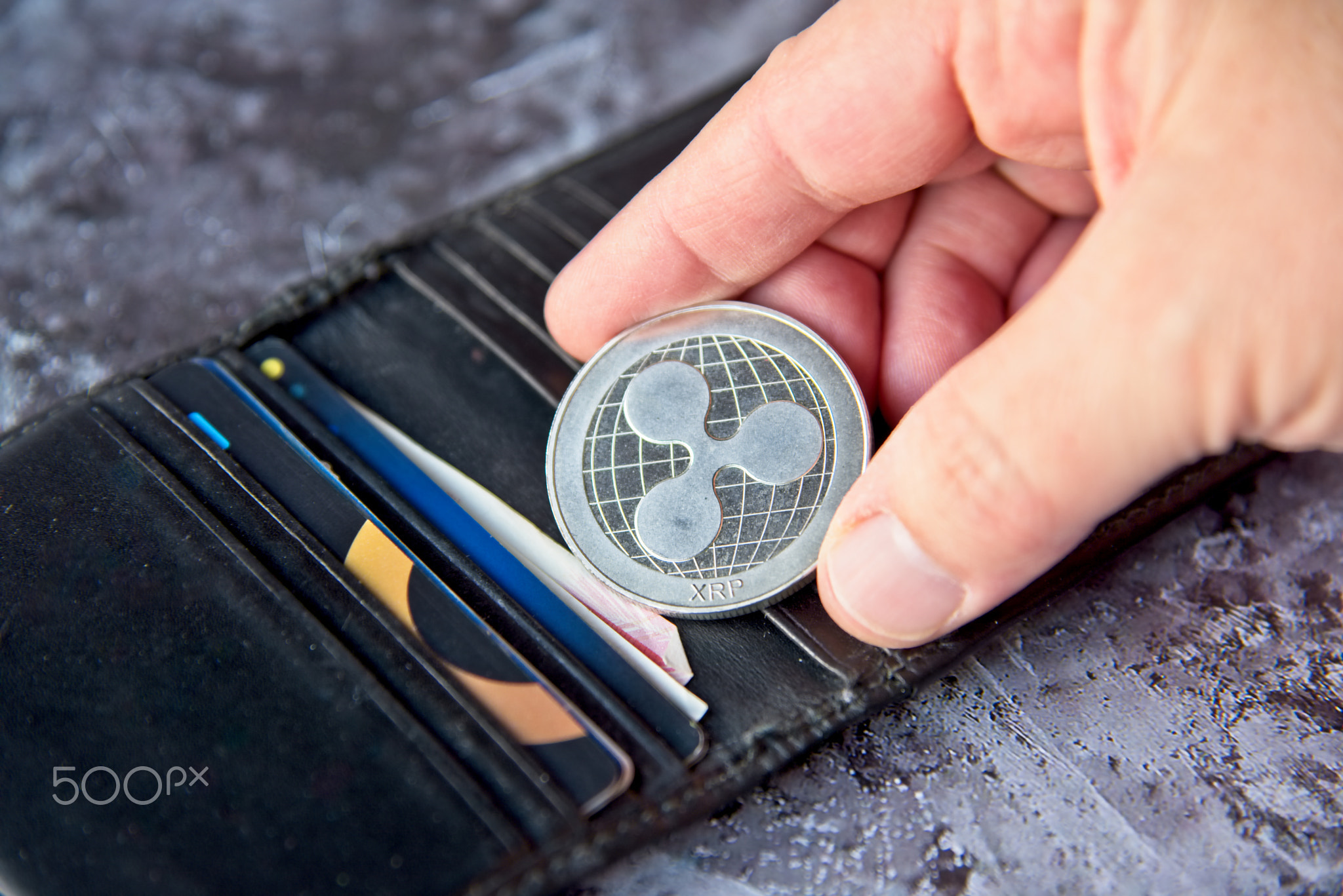 Crypto coin, XRP Ripple coin in leather wallet on concrete style