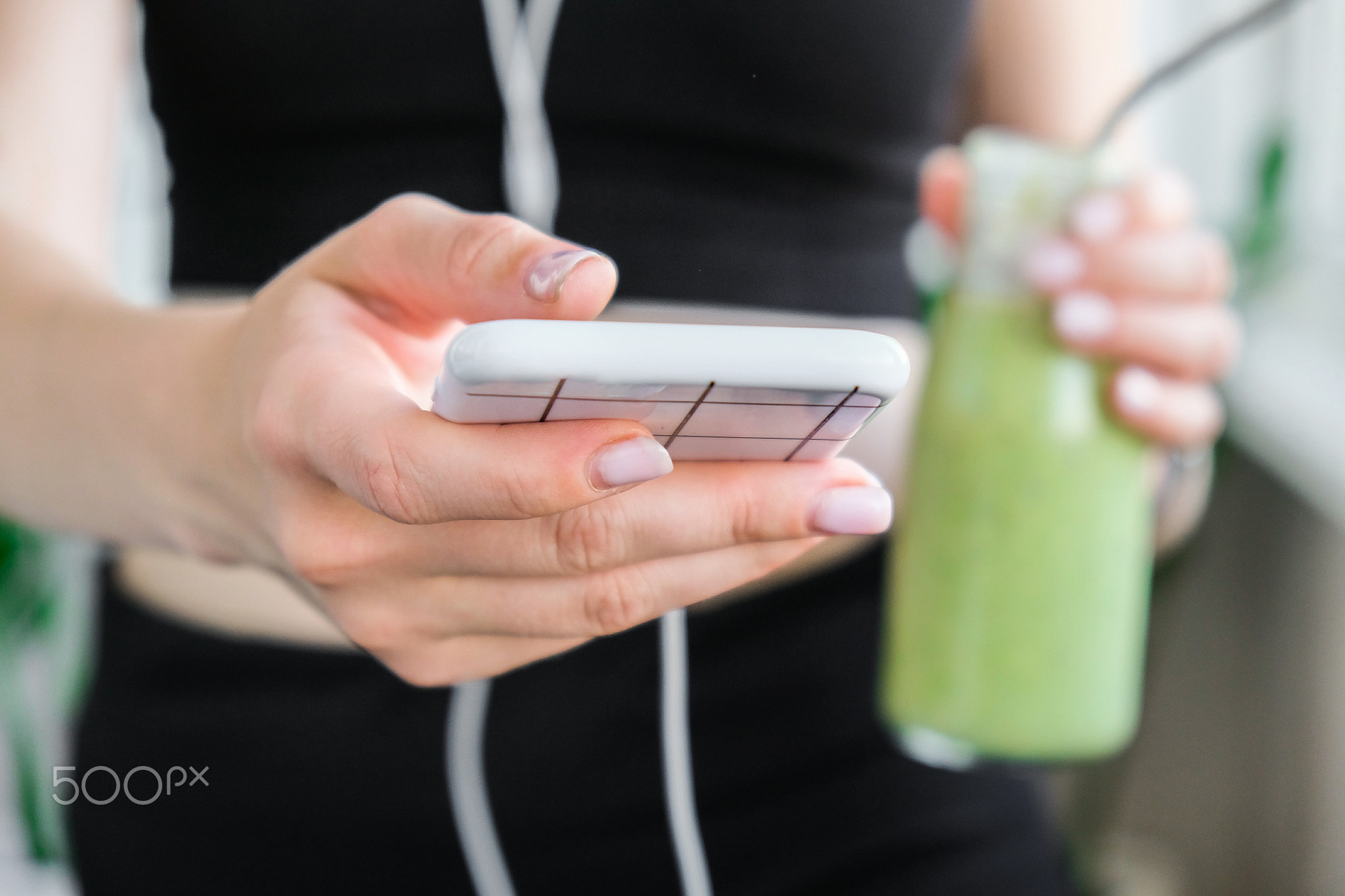 Young millenial woman checking smartphone drinking vegan smoothie