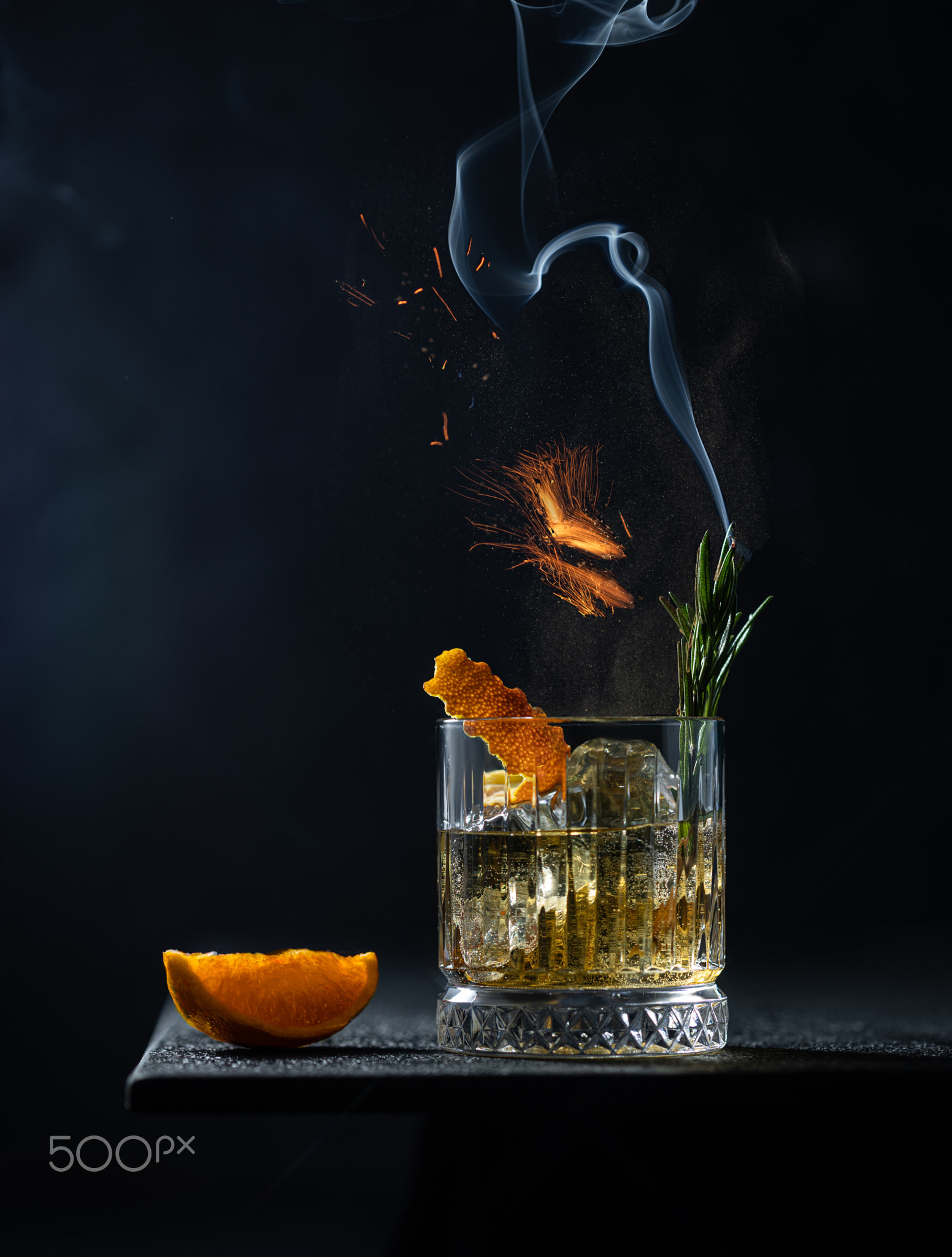 Whiskey or cognac in cristal glass with smoked rosemary,fire and slice