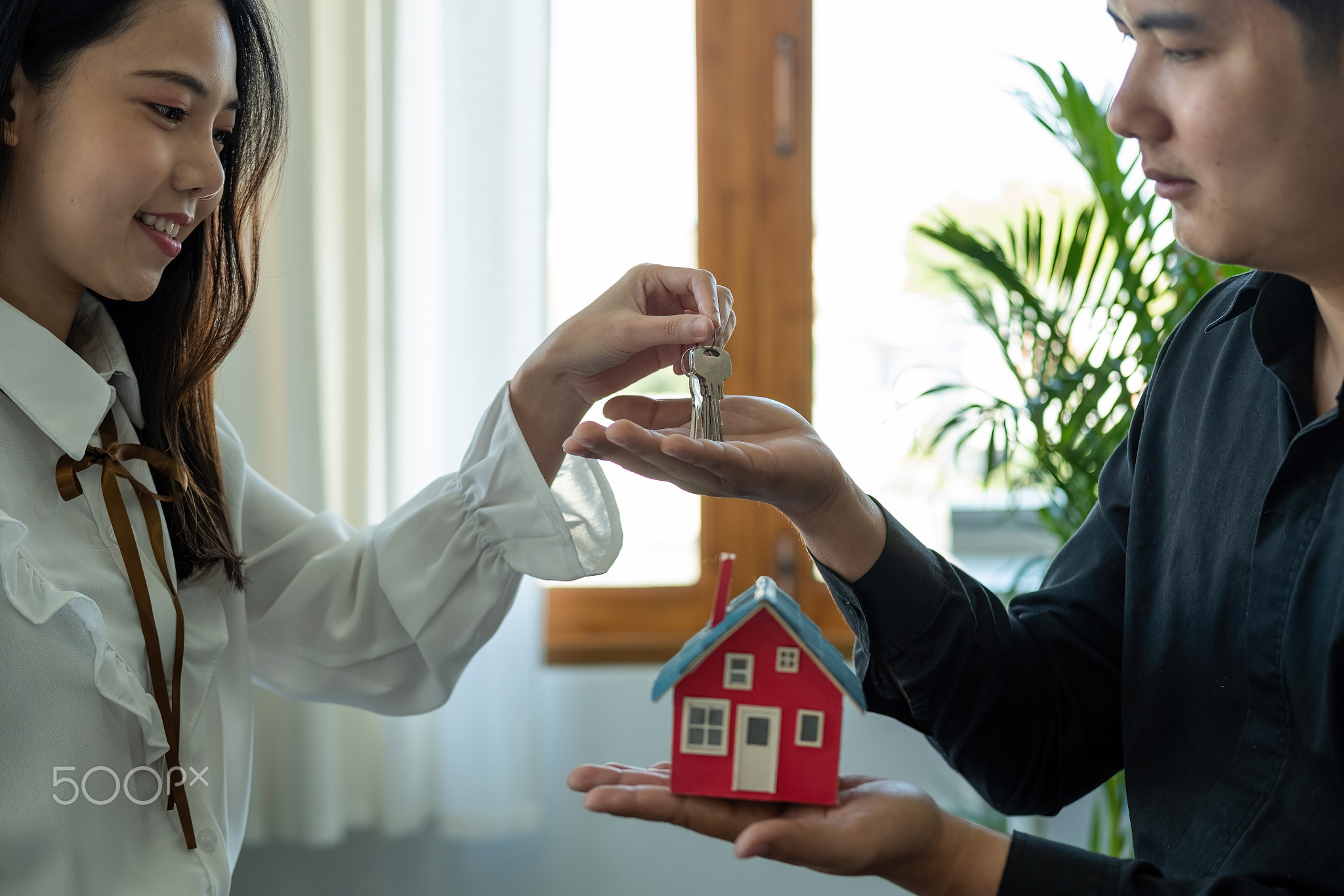 real estate agent holding house key to his client after signing