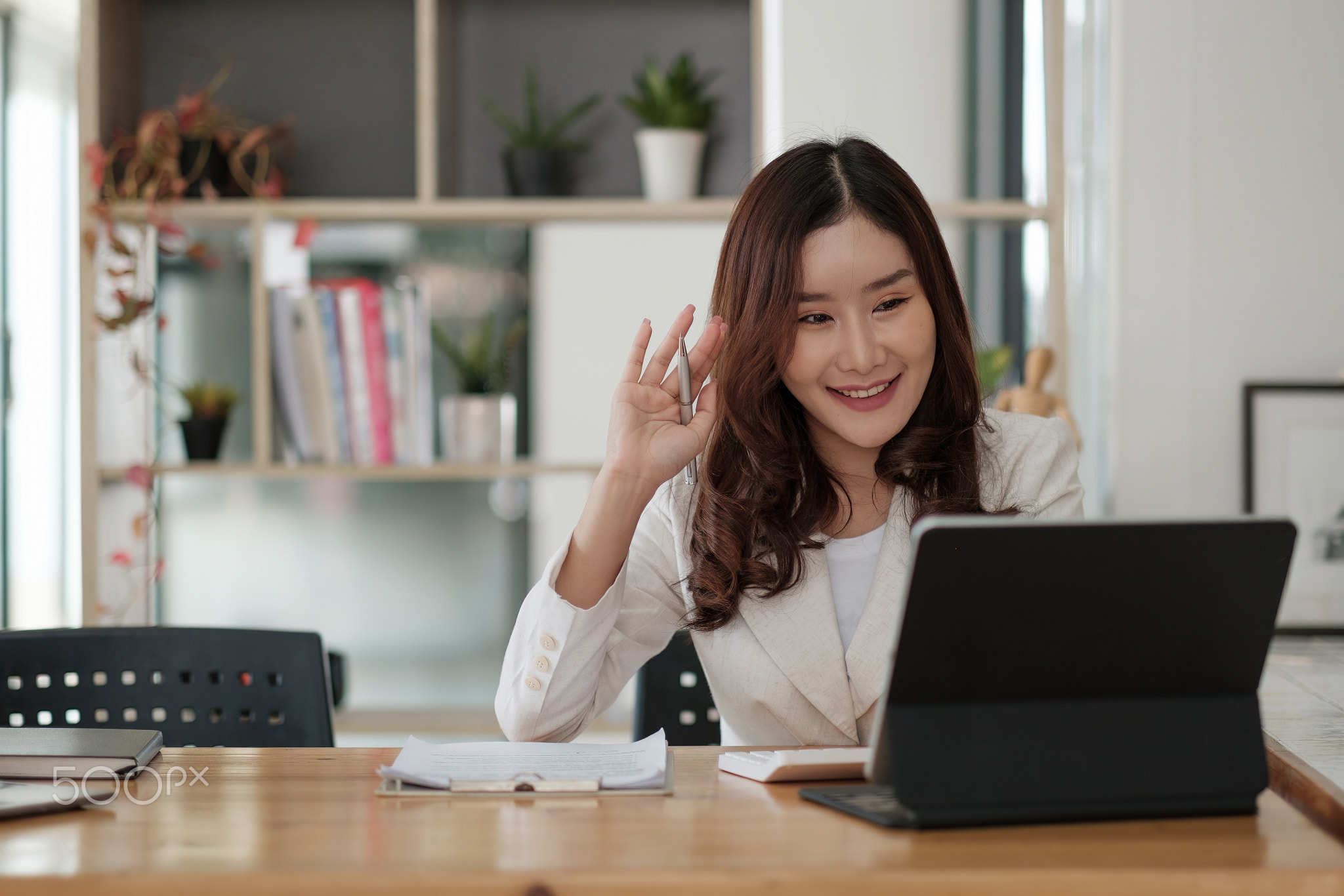 Portrait of smiling asian woman waving hello talking on video call