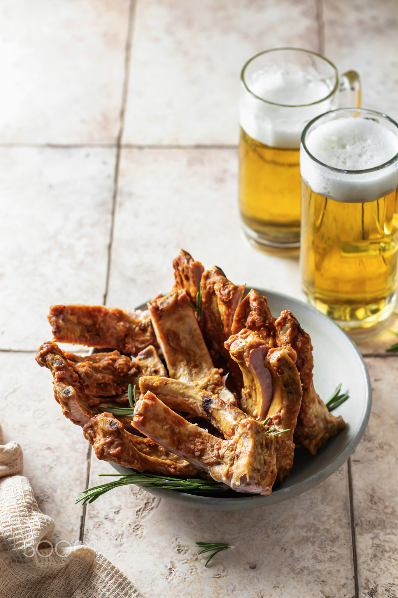 Smoked pork ribs with rosemary, beer and napkin on pink tile