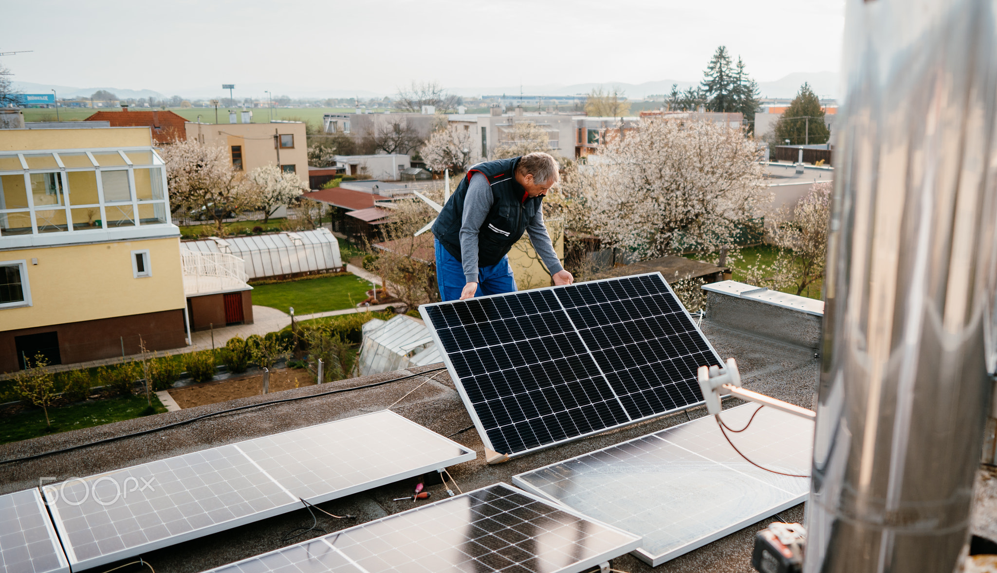 Worker installing new solar panels on roof of family house. Eco