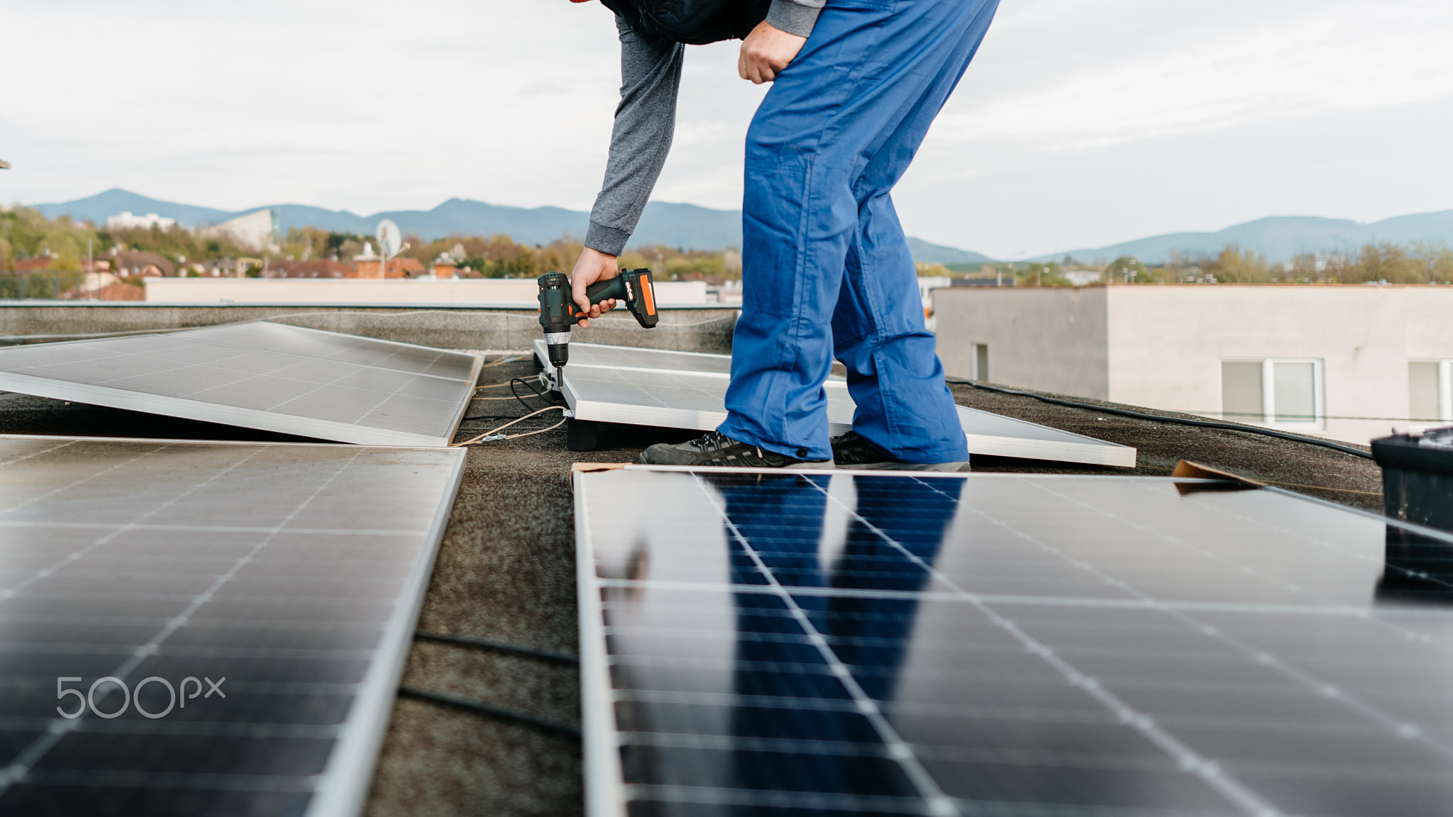 Worker installing new solar panels on roof of family house