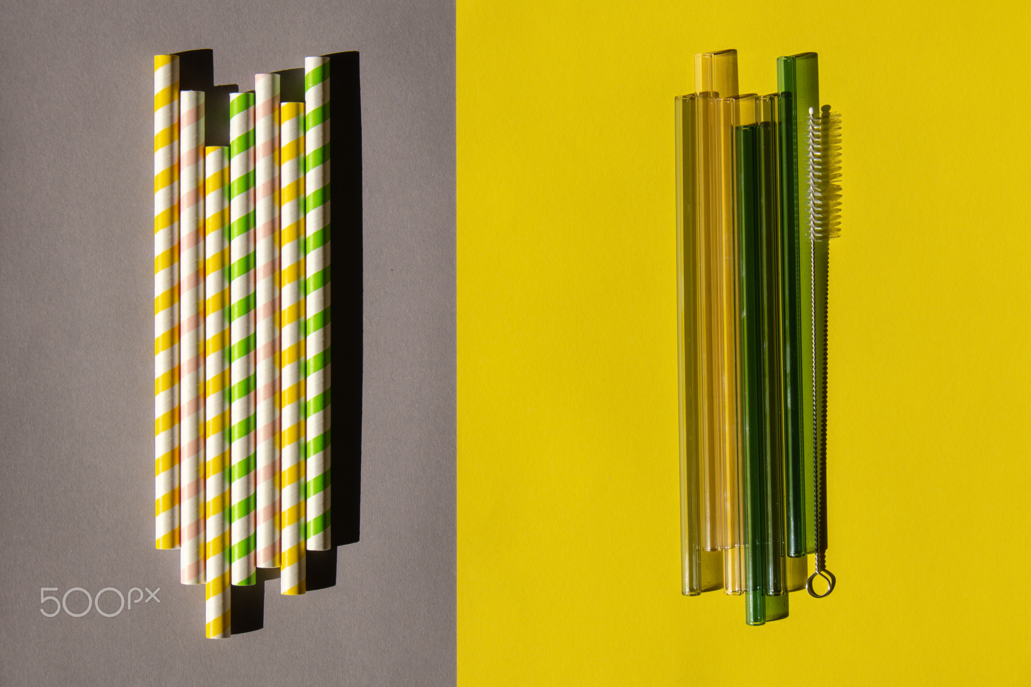 Reusable glass Straws with paper straws on colorful background Eco