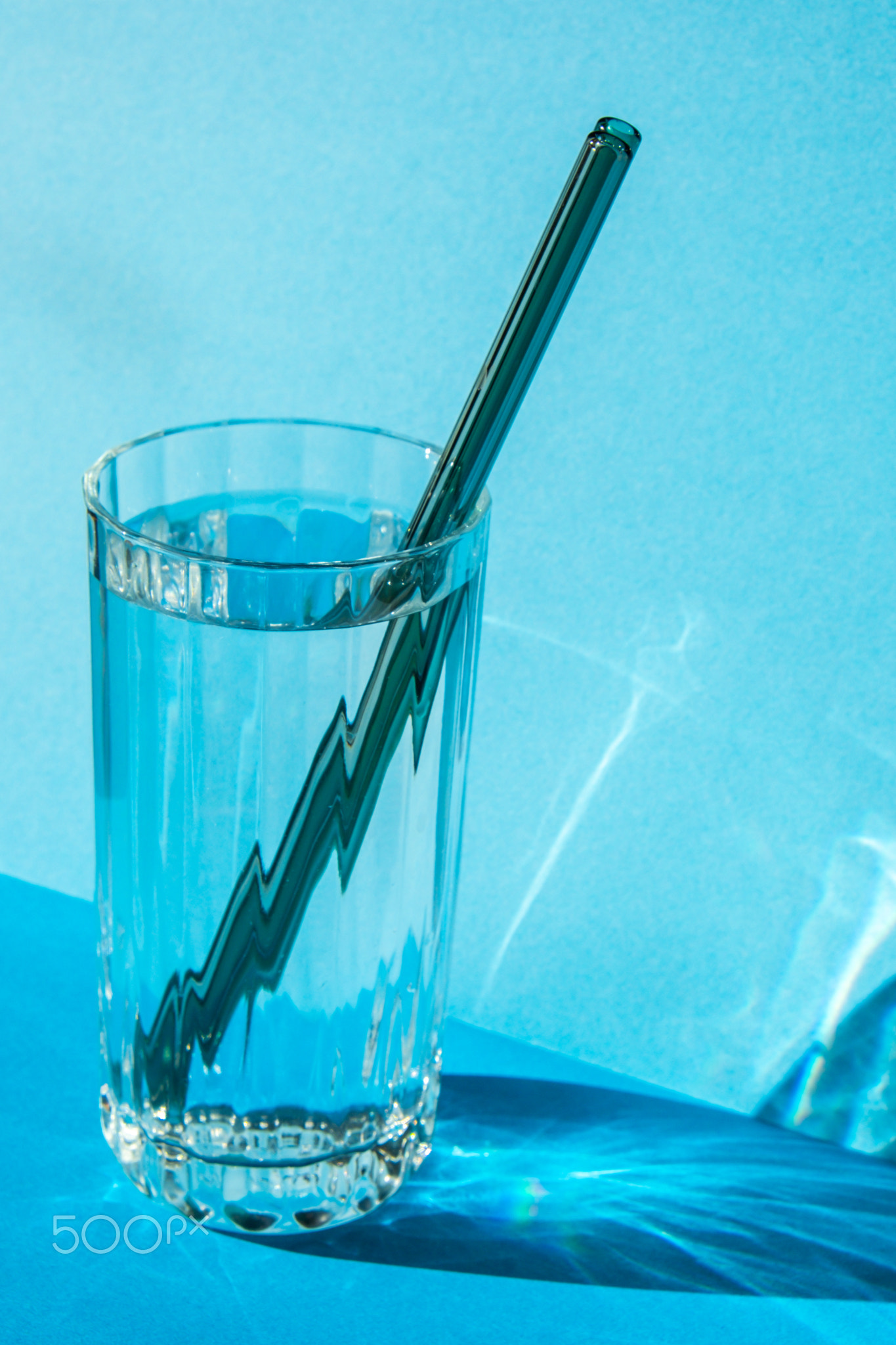 Reusable glass Straws in Glass with water on blue background Eco