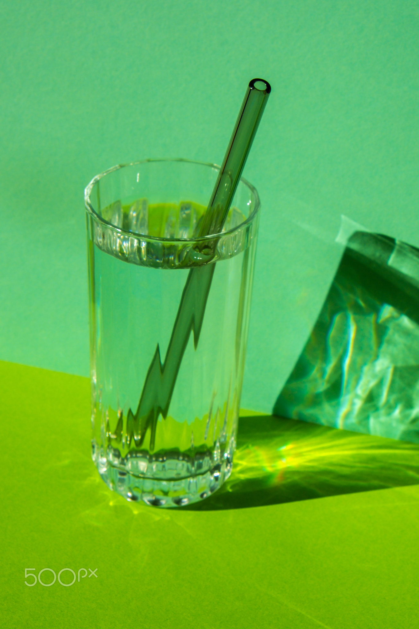 Reusable glass Straws in Glass with water on green background Eco