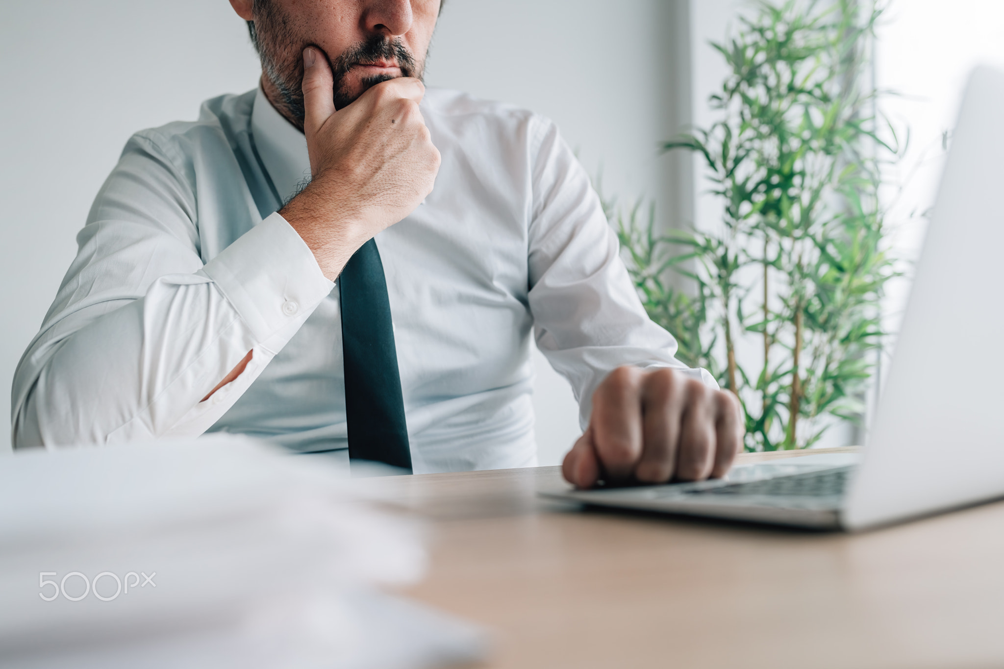 Businessman during video call, looking at laptop screen and listening to a speaker