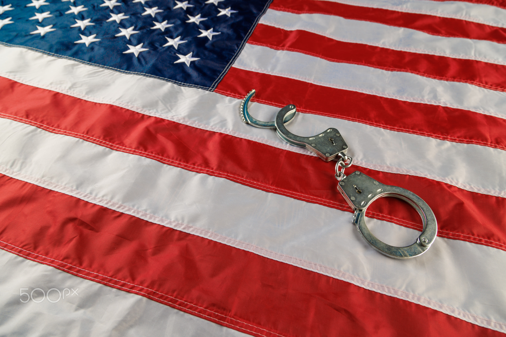 silver metal handcuffs over US flag on flat surface