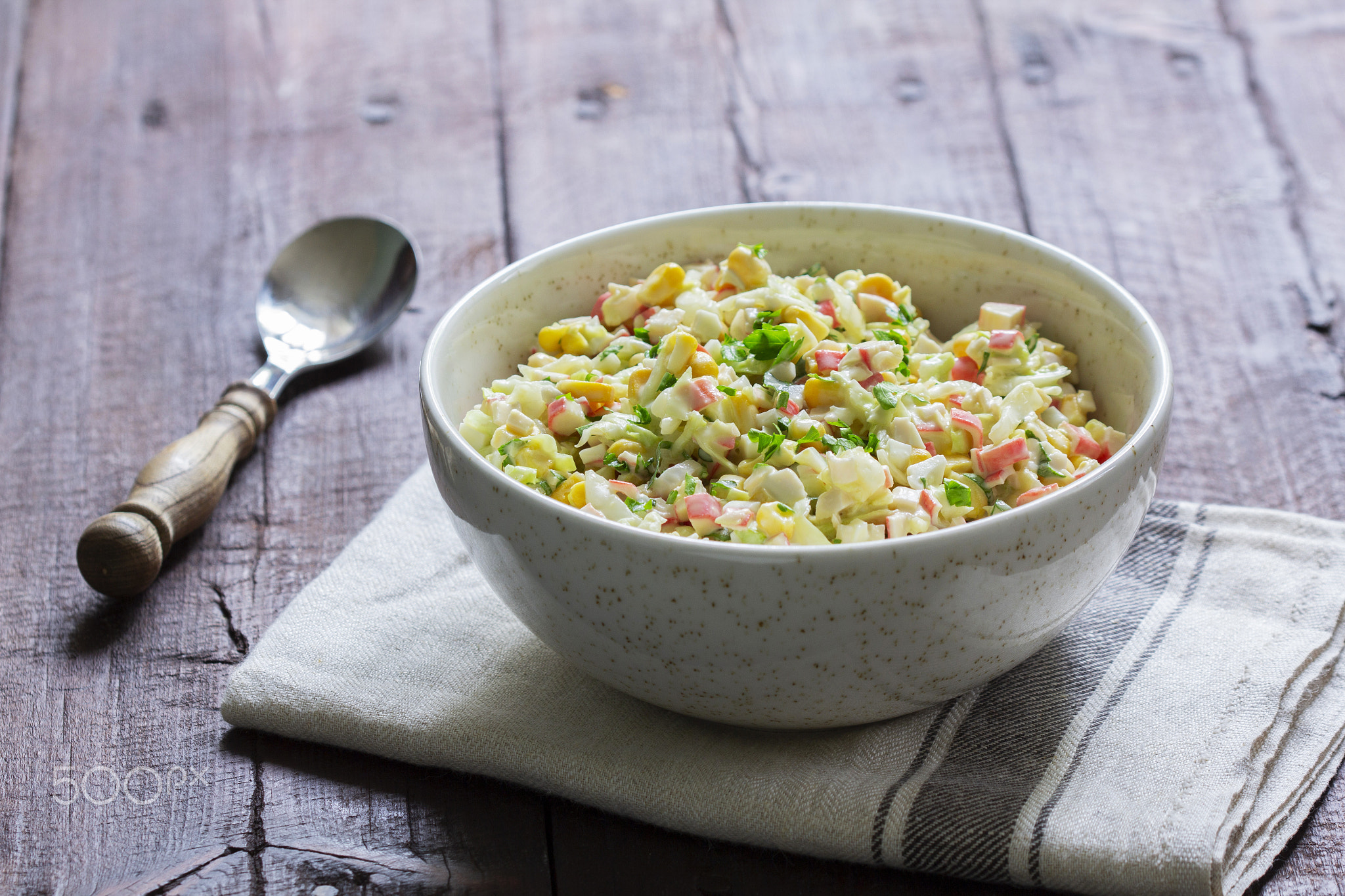 Vegetable salad with crab sticks, dressed with mayonnaise.