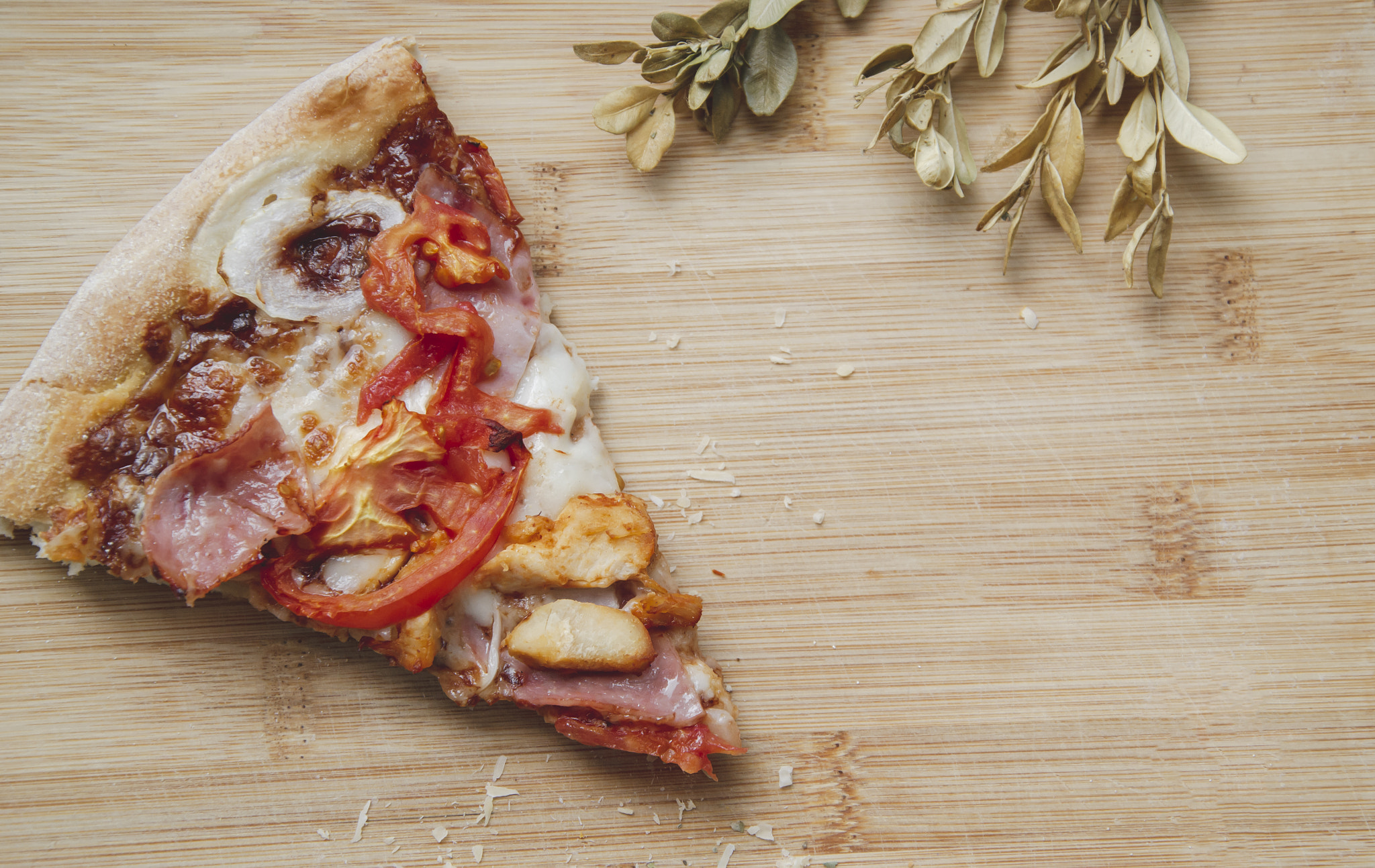 picture of pizza slice with tomato chicken ham and mushrooms from the top view